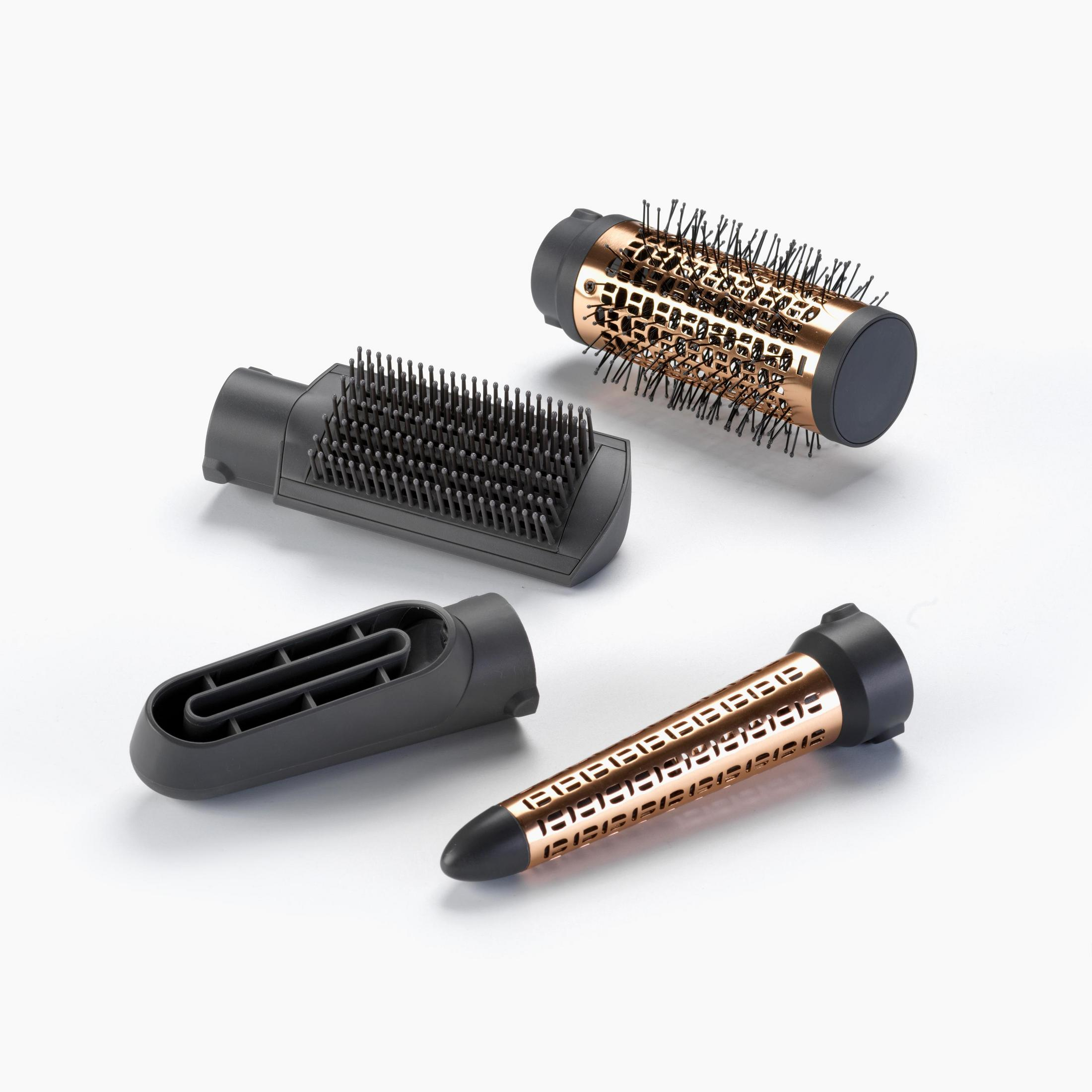 Cztery nasadki do stylizacji włosów: okrągła szczotka, płaska szczotka, dysza i stożkowa nasadka. Na białej powierzchni.