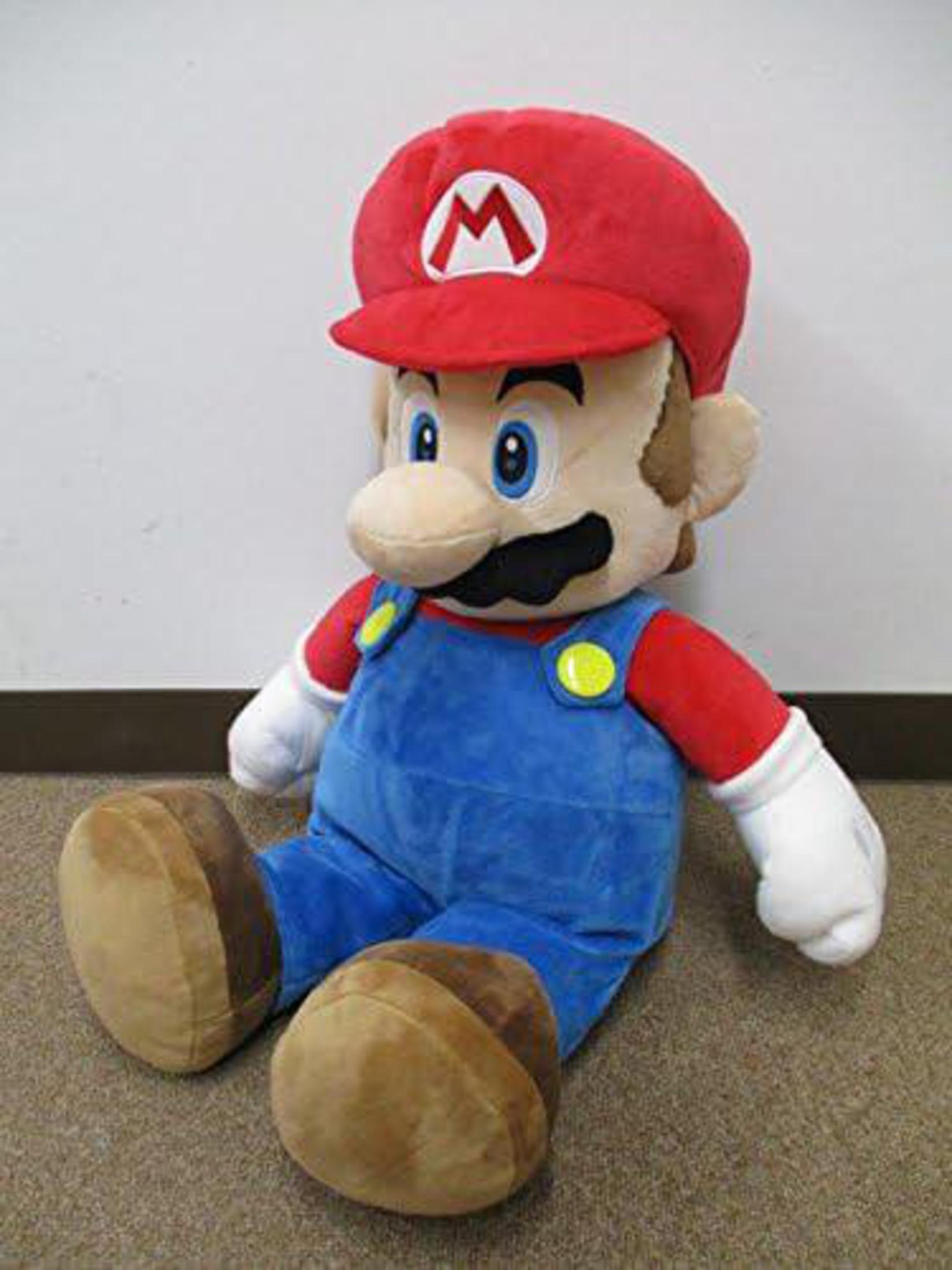 Grande bambola di peluche di Mario. Indossa il suo classico cappello rosso, la tuta e i guanti bianchi.