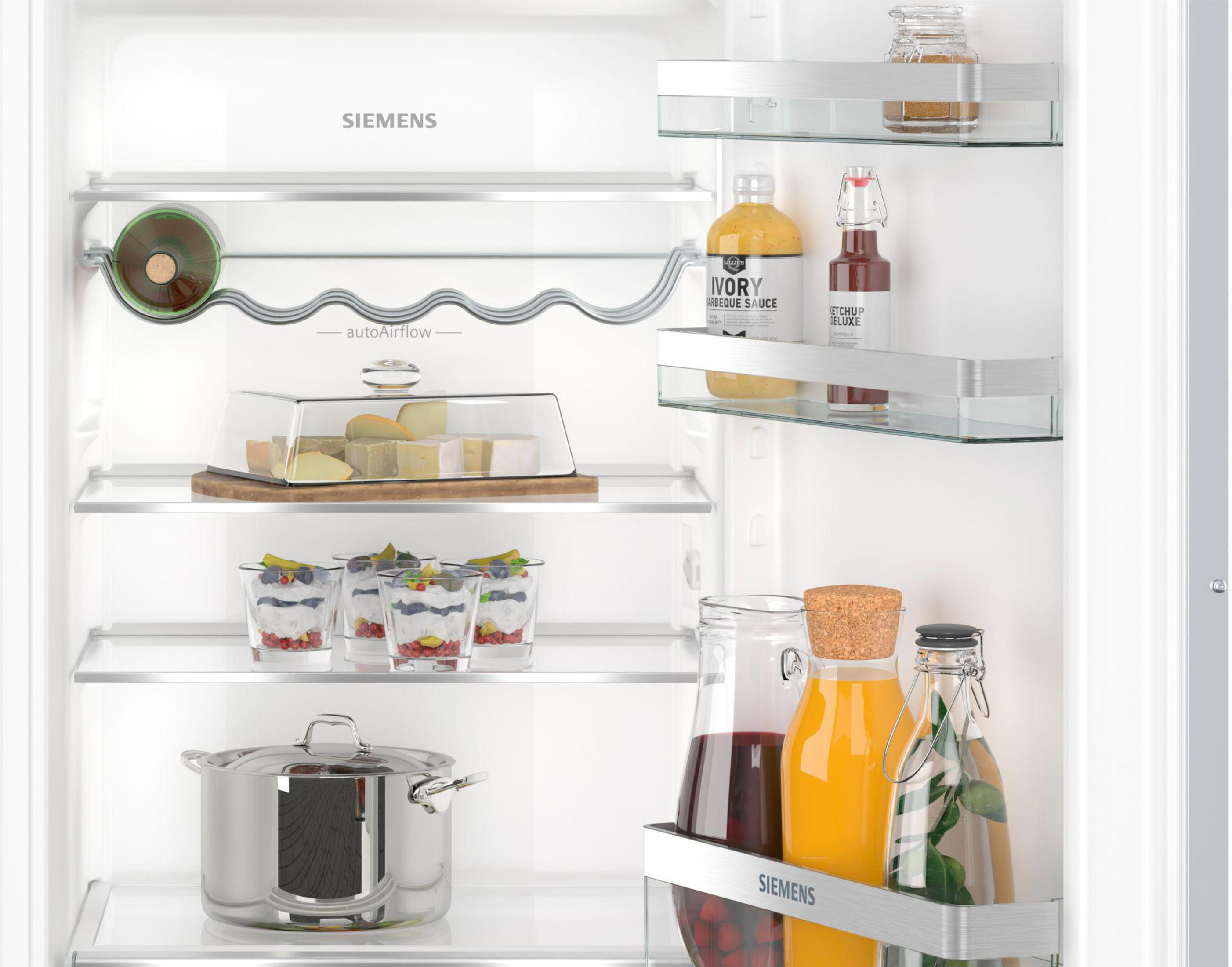 Offener Kühlschrank mit Regalen voller Lebensmittel, darunter Gläser, Flaschen und zubereitete Desserts.