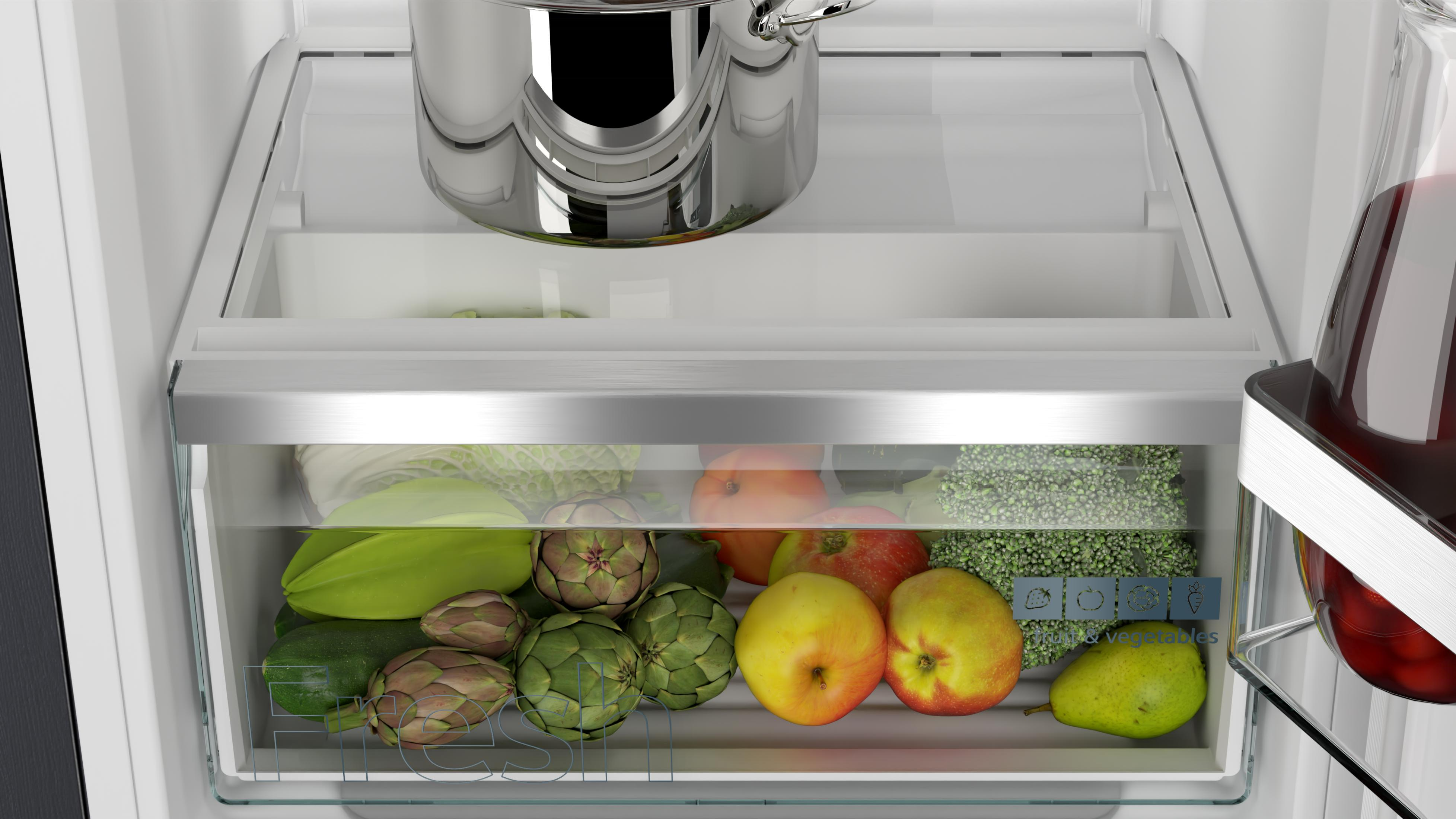 In einer Kühlschublade werden Gemüse wie Zucchini, Artischocken, Äpfel und Brokkoli gelagert. Ein Topf steht oben.