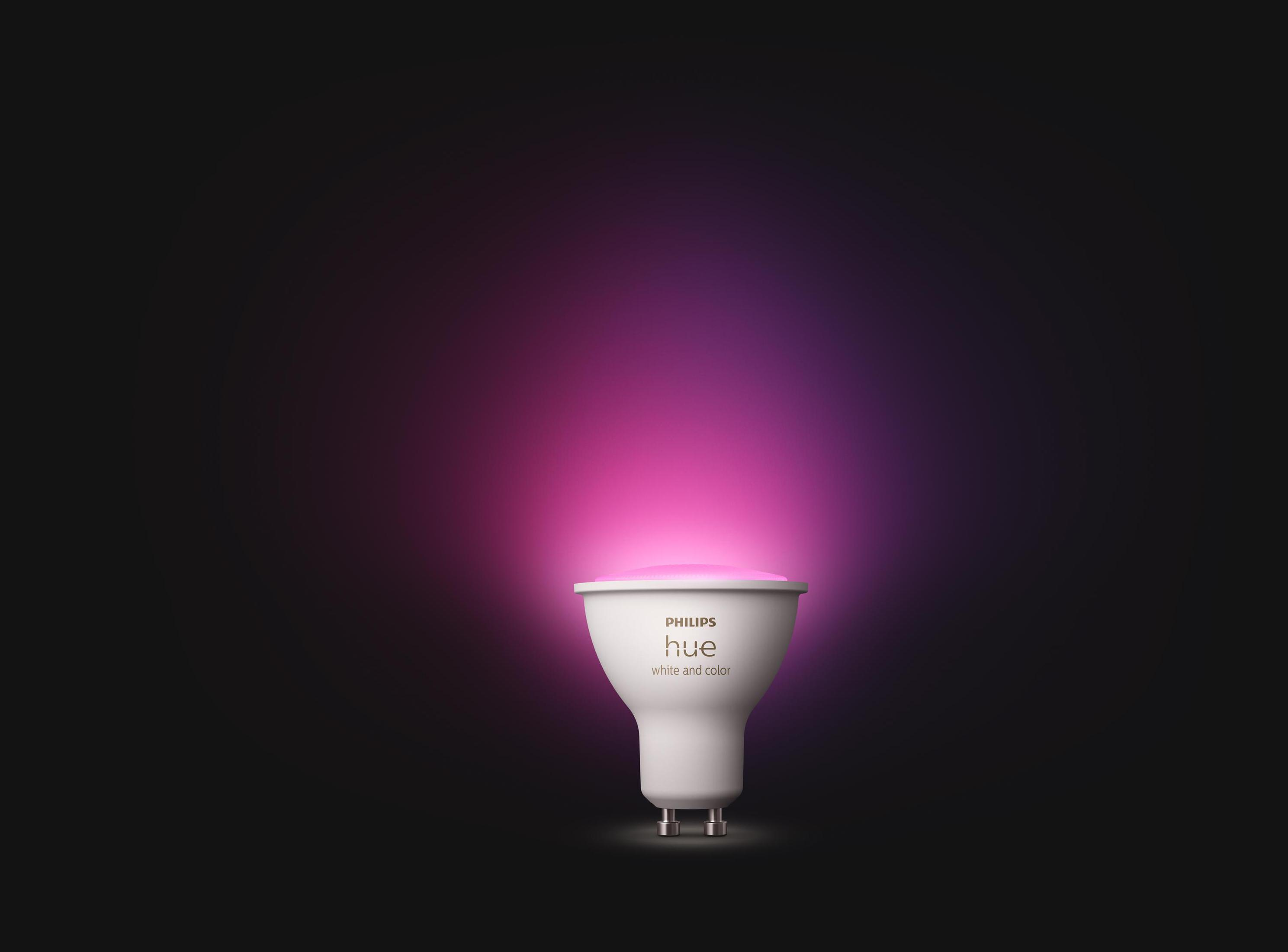 Philips Hue Weiß- und Farblampe. Rosa Licht emittiert. Weiße Glühbirne mit silbernem Sockel, schwarzer Hintergrund.