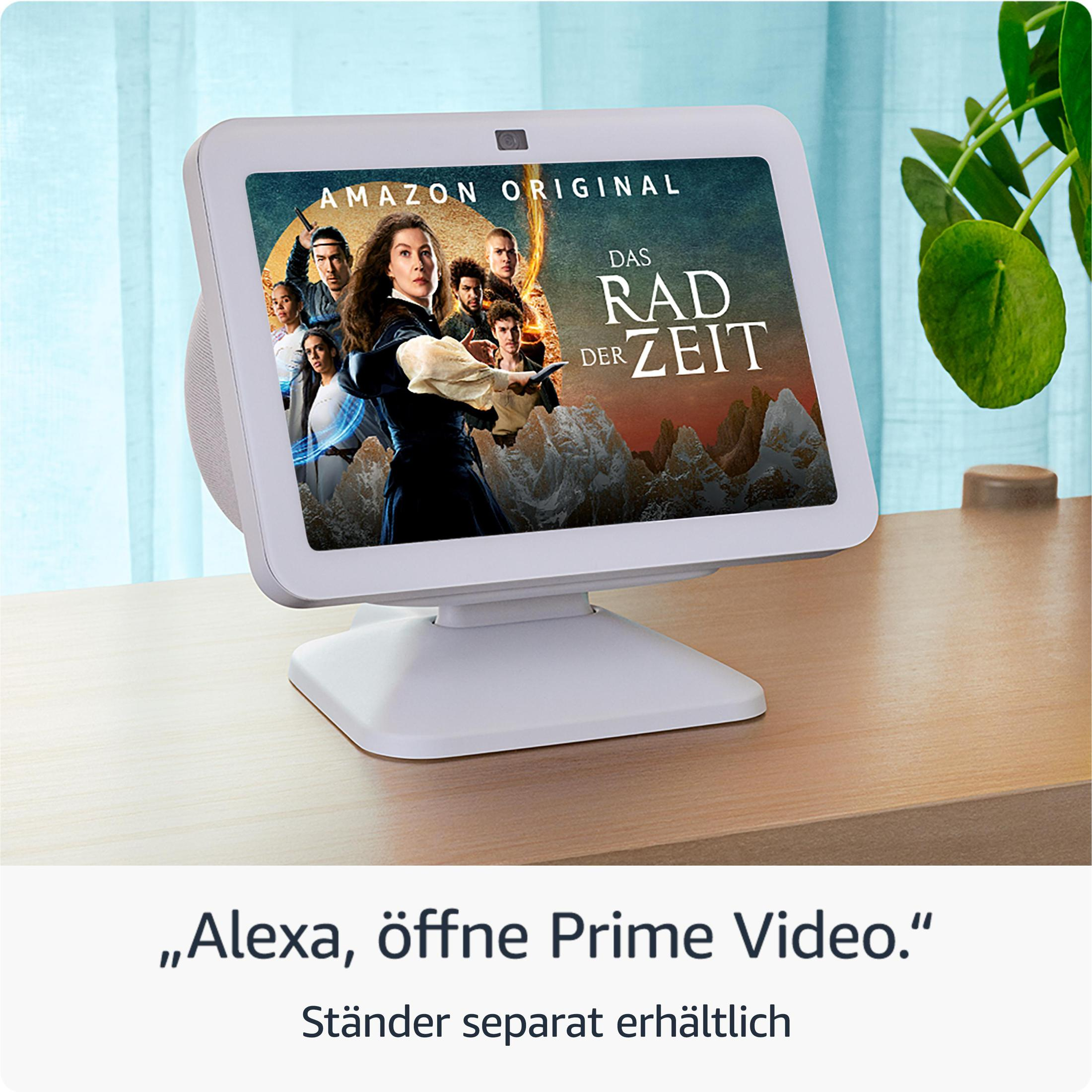 Amazon Echo Show na drewnianym stole, wyświetlający scenę z programu telewizyjnego.