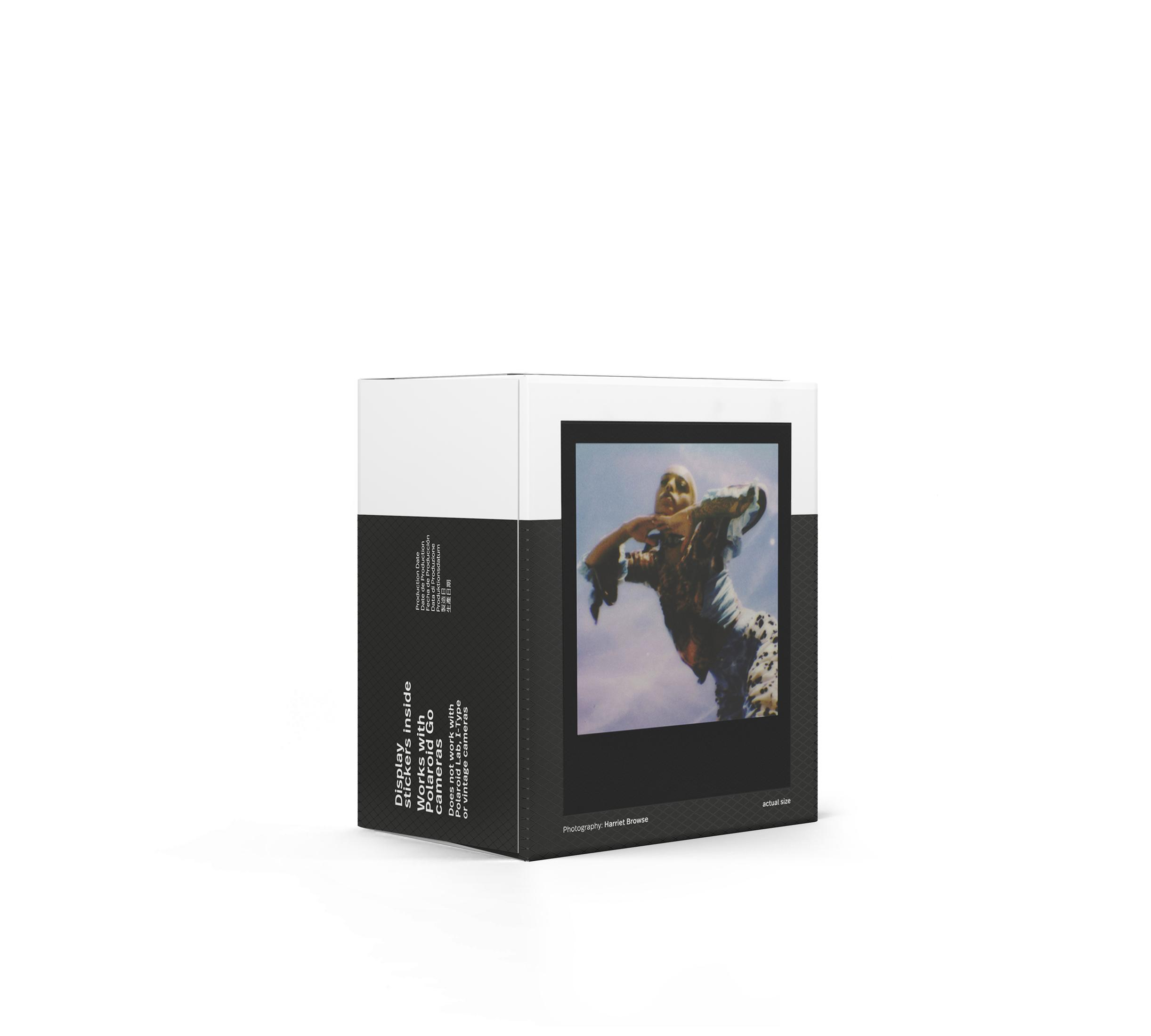Caja con una polaroid. La foto muestra a una persona en el aire. Blanco y negro con algo de color.
