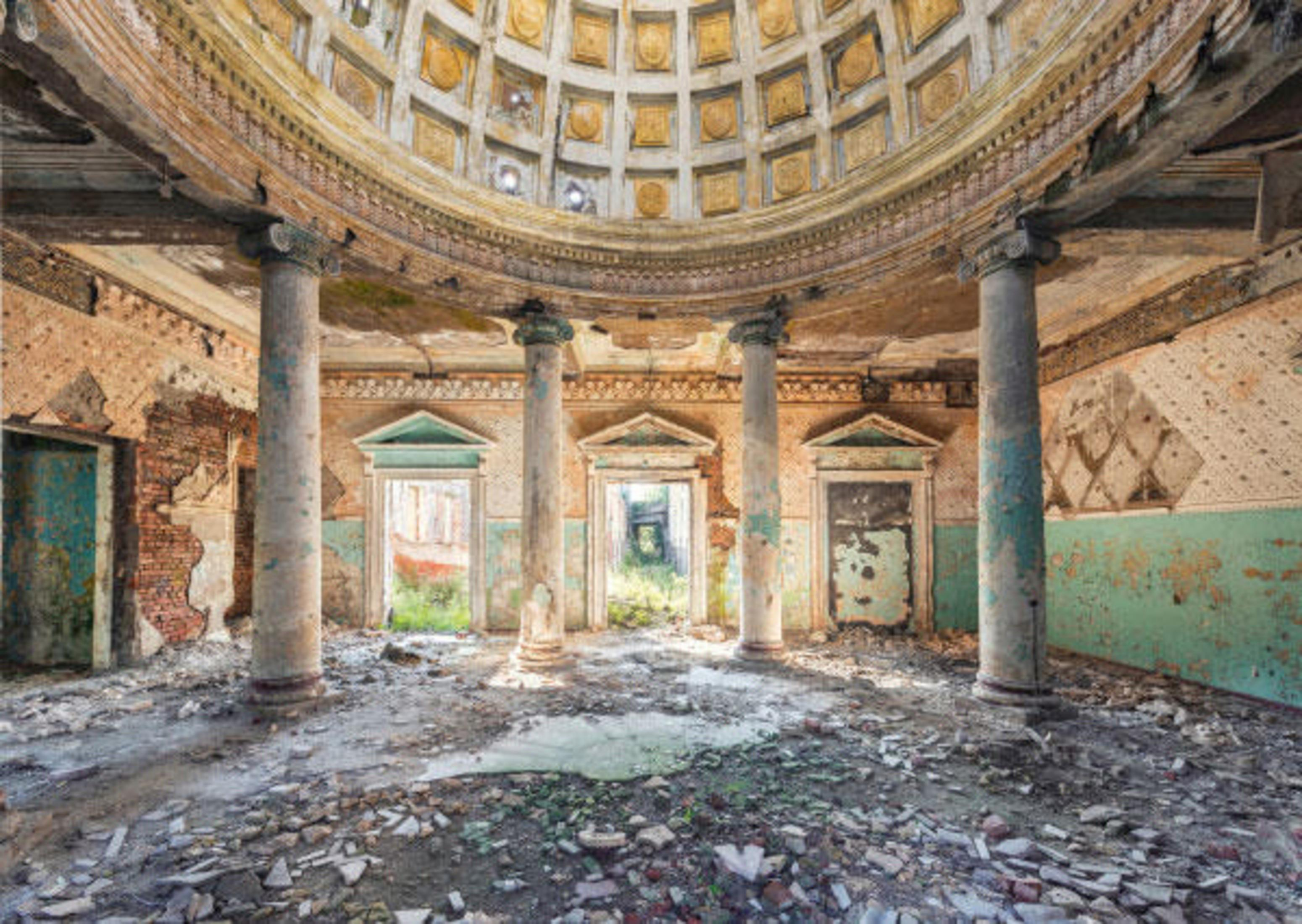 Interior de un edificio arruinado y abovedado. Columnas, paredes desmoronadas y escombros en el suelo.