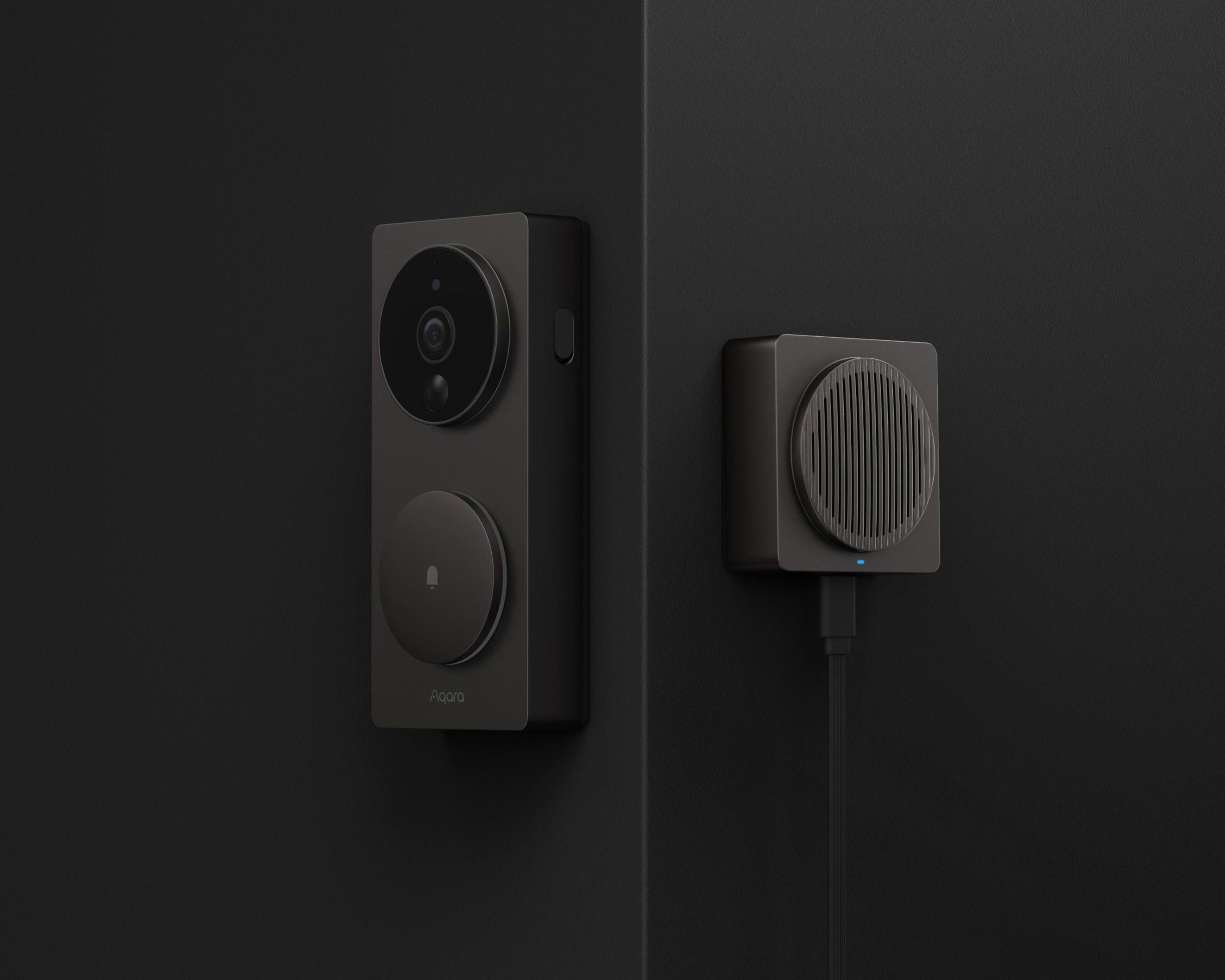 Ein dunkelgraues Smart-Türklingelsystem mit zwei Teilen: einer Kamera und einem Gong, an einer schwarzen Wand montiert.