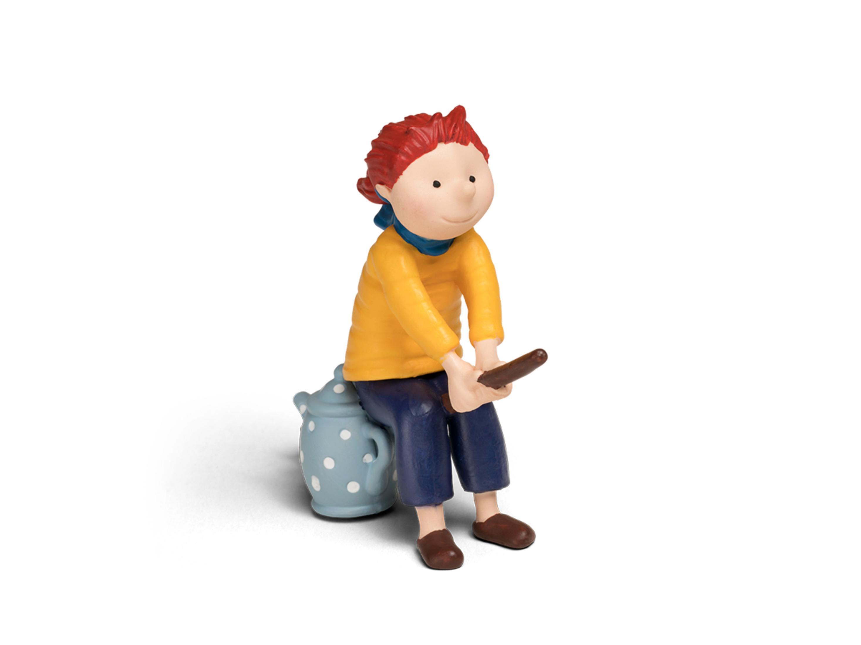 Eine Jungenfigur sitzt auf einem Hocker und hält einen kleinen braunen Stock.