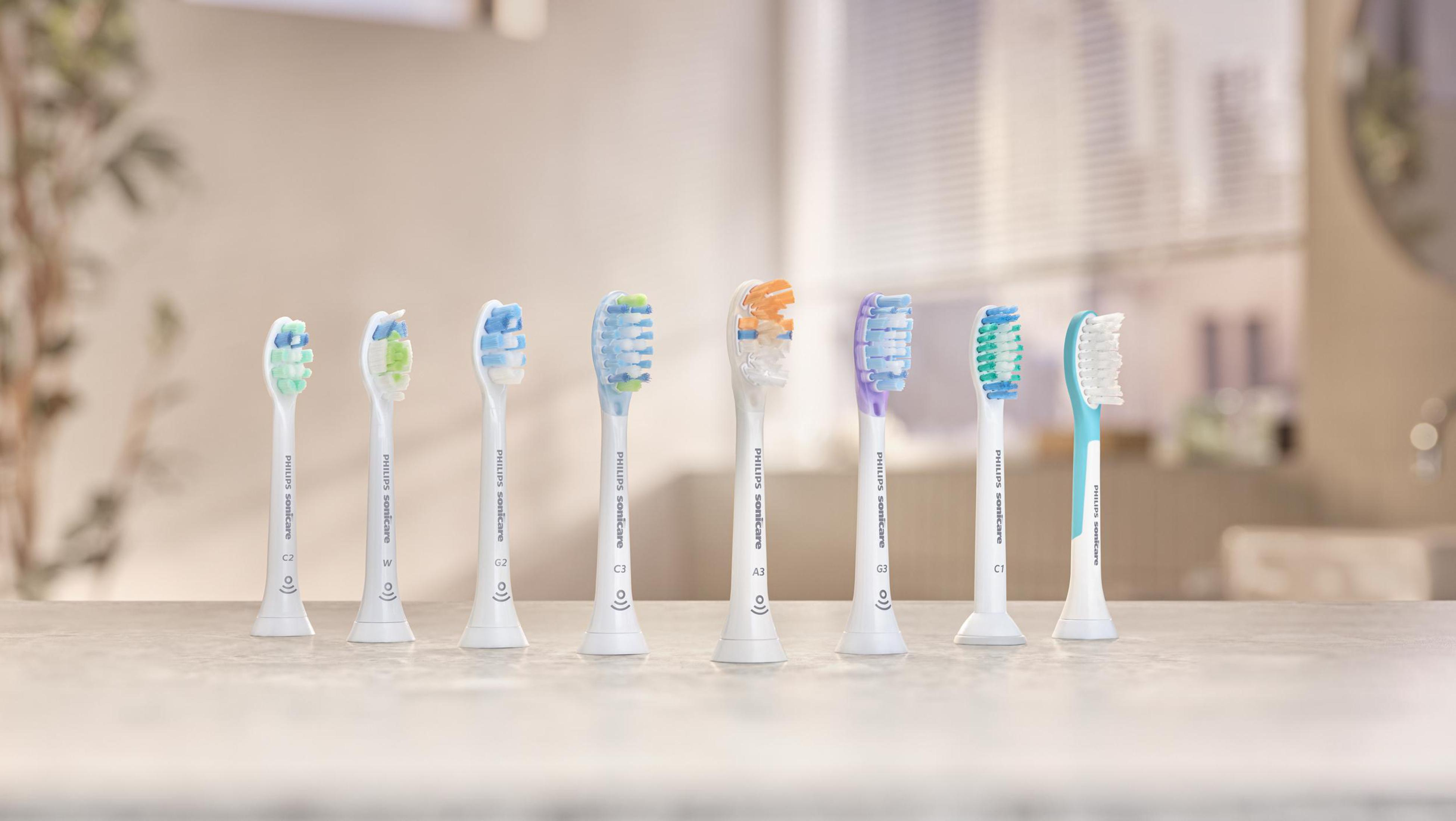 Osiem końcówek do szczoteczki Philips Sonicare w różnych kolorach na blacie z rozmytym tłem.