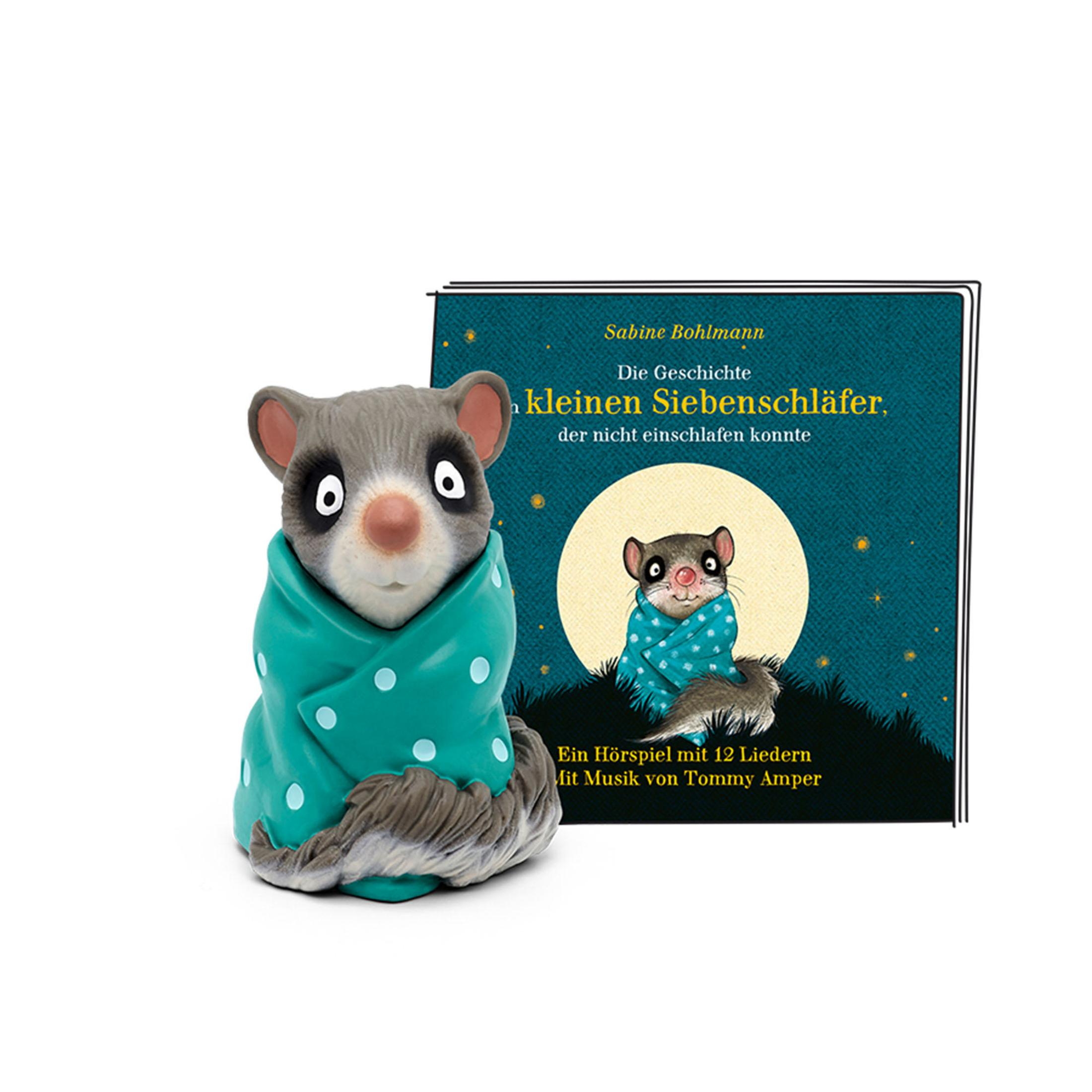 Eine Siebenschläfer-Figur in eine Decke gehüllt mit einem Buch daneben. Das Buch zeigt einen Siebenschläfer.