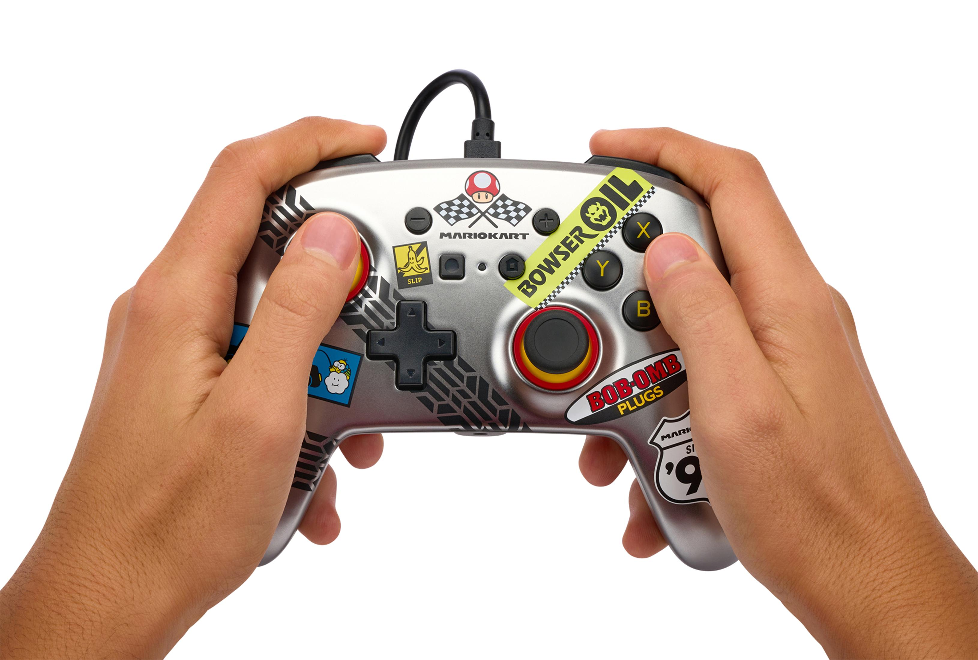 Hände halten einen silbernen Mario Kart-Controller mit verschiedenen Aufklebern.