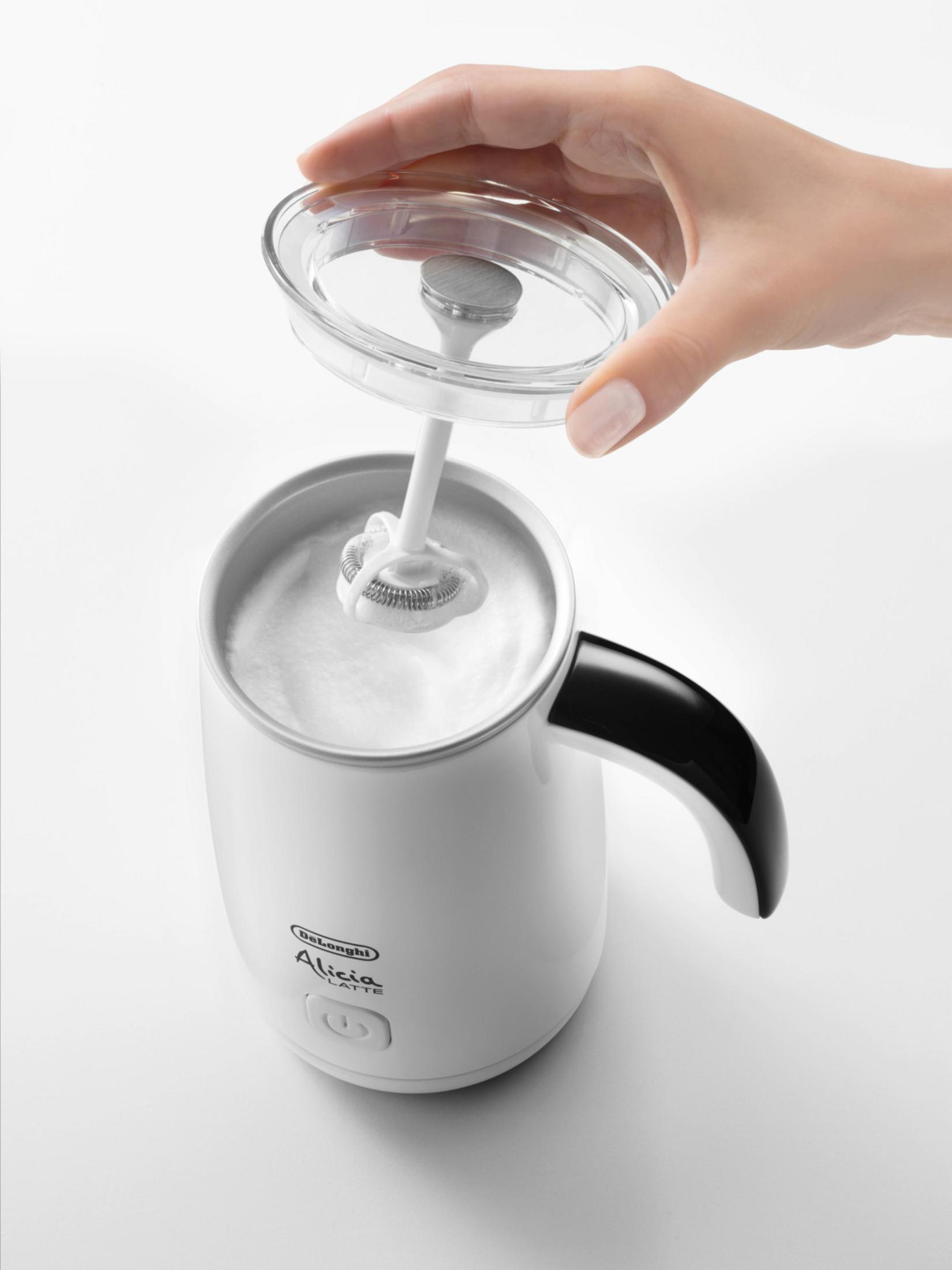 Biały spieniacz do mleka De'Longhi Alicia Latte z przezroczystą pokrywką. Ręka otwiera pokrywkę.