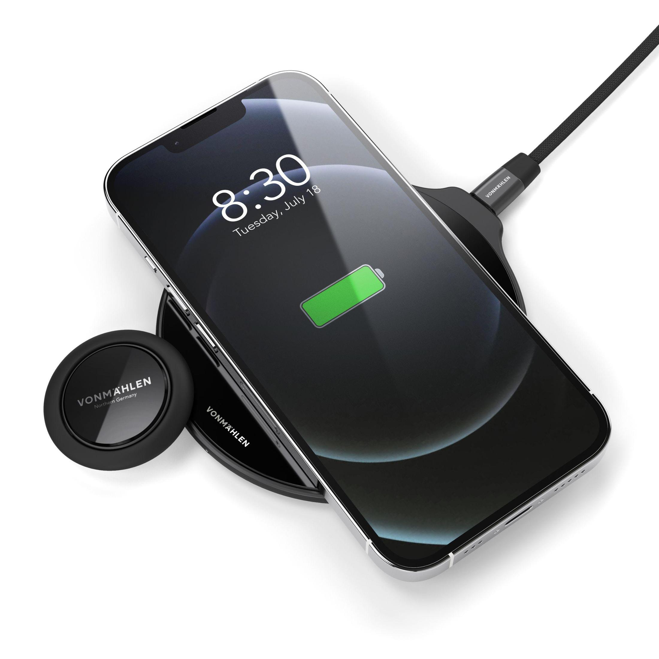 Schwarzes Telefon, das auf einem schwarzen Ladepad geladen wird. Telefon zeigt Uhrzeit und Akkustand.