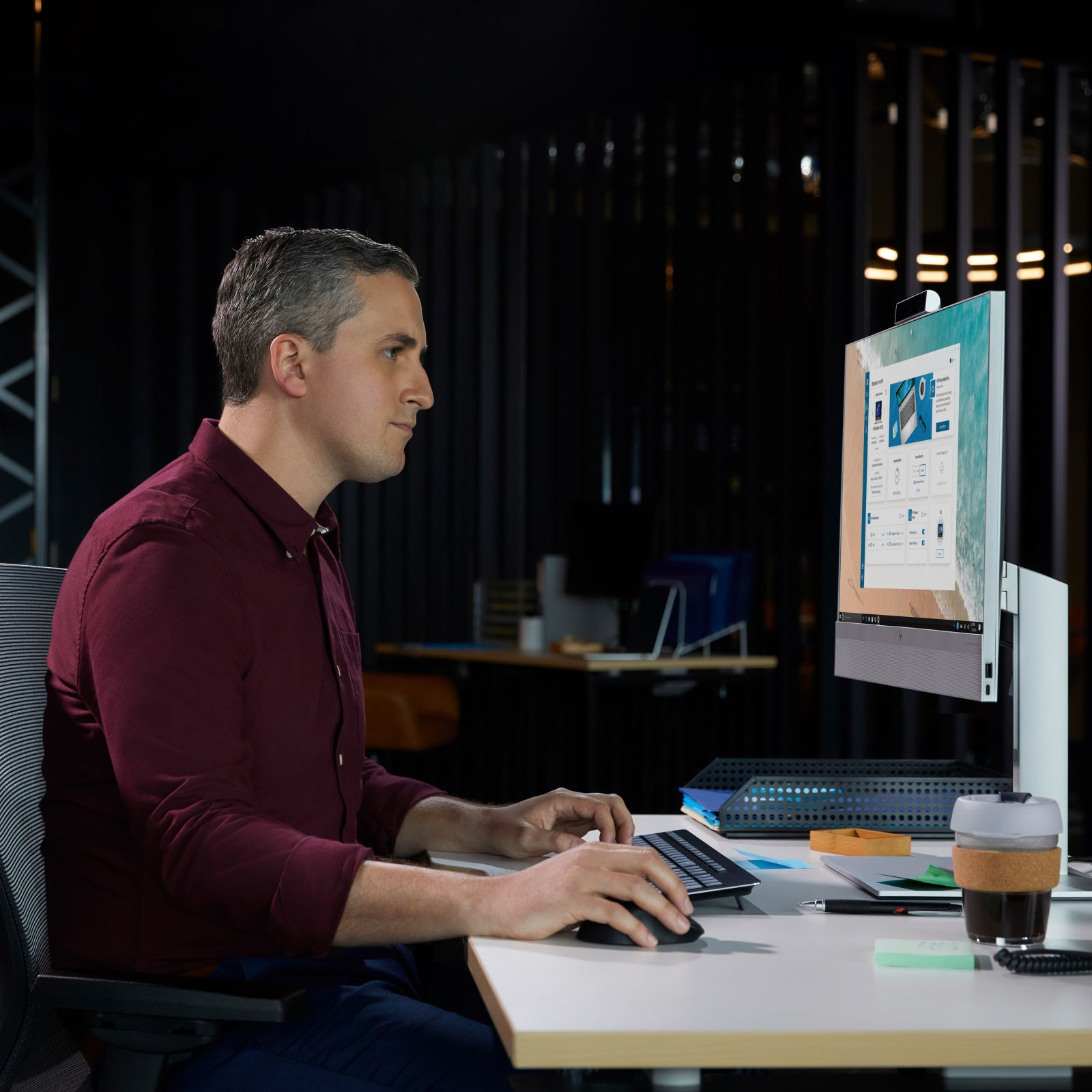 Mann, der an einem Computer an einem Schreibtisch arbeitet. Schwarzer Hintergrund.