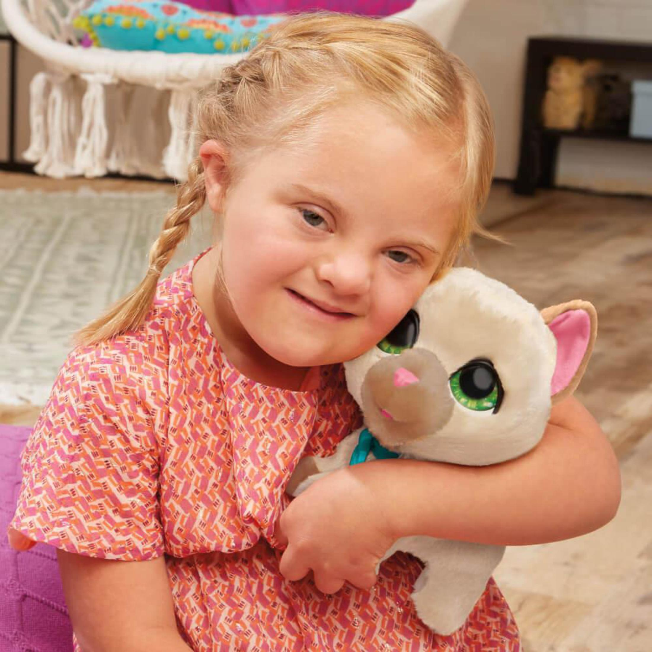 Dziewczynka przytula pluszowego kota. Dziewczynka ma blond warkocze i zespół Downa. Kot jest biało-beżowy.