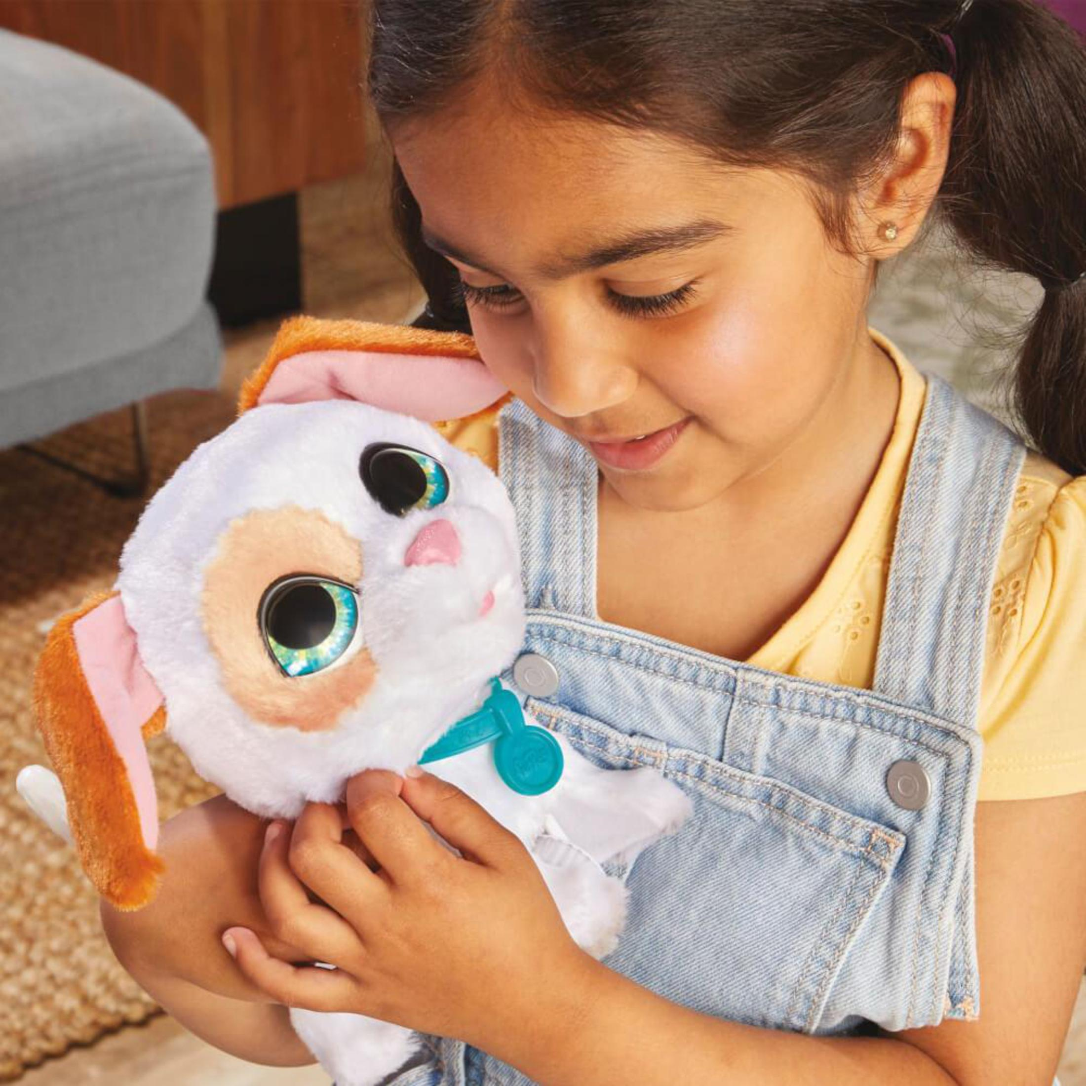 Dziewczynka trzyma pluszową zabawkę psa. Pies jest biały i ma niebieską obrożę.