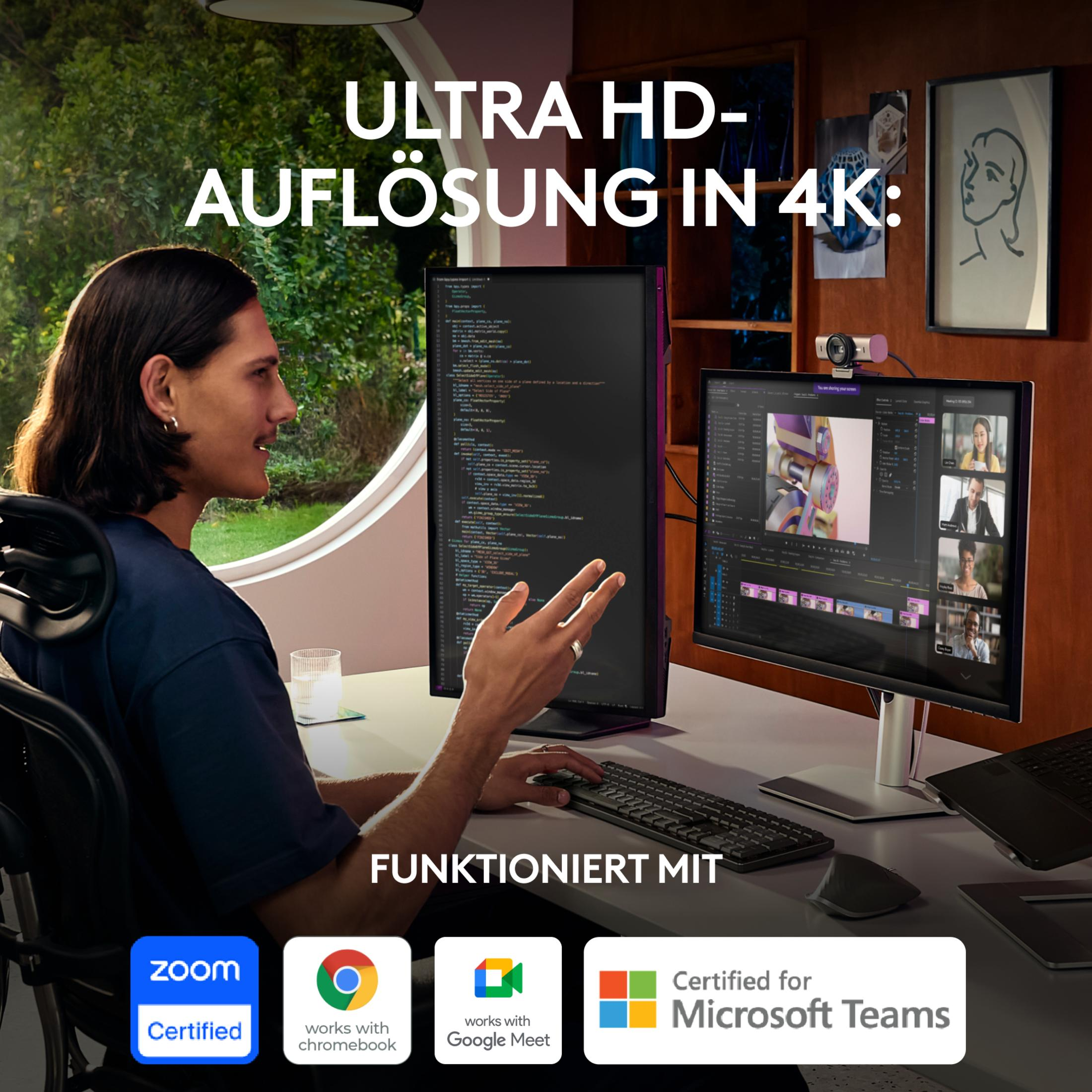 Mężczyzna przy biurku używający komputera, monitor pokazuje kodowanie i wideokonferencję.