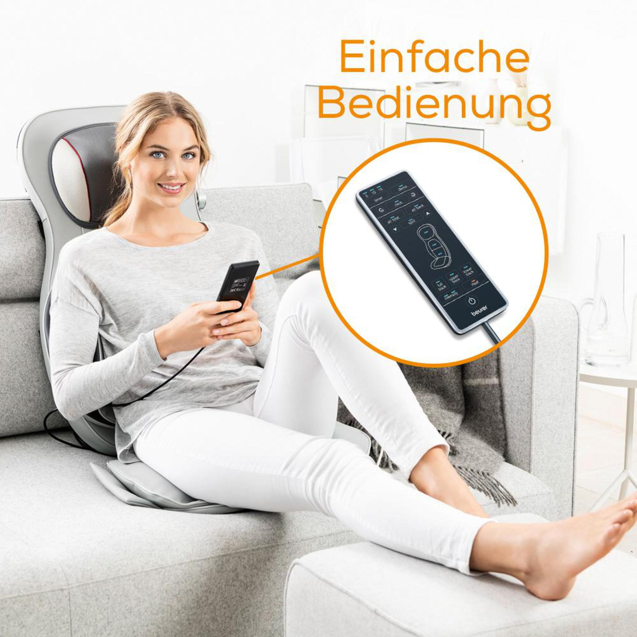 Frau sitzt auf einem Sofa und bedient eine Fernbedienung mit einem Massagekissen. Der Text lautet 'Einfache Bedienung'.
