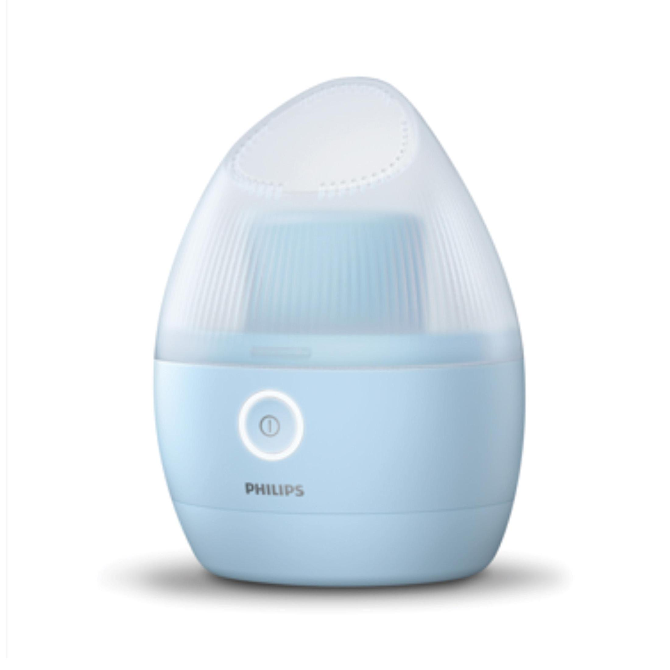 Açık mavi bir Philips yüz buhar makinesi. Beyaz bir üst kısma ve bir güç düğmesine sahiptir. Marka adı aşağıdadır.