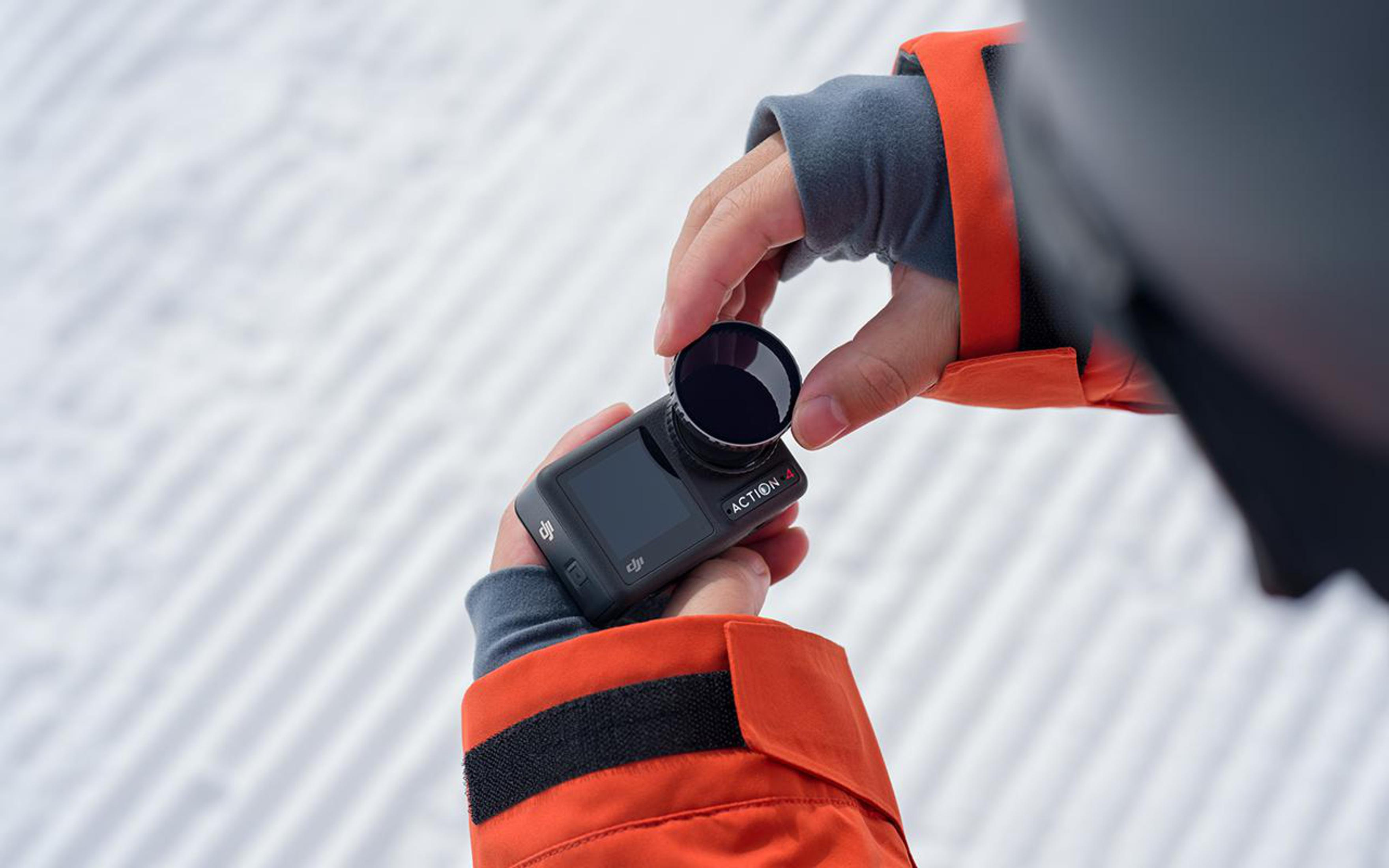 Ręce osoby używającej aparatu. Mocują obiektyw do aparatu.