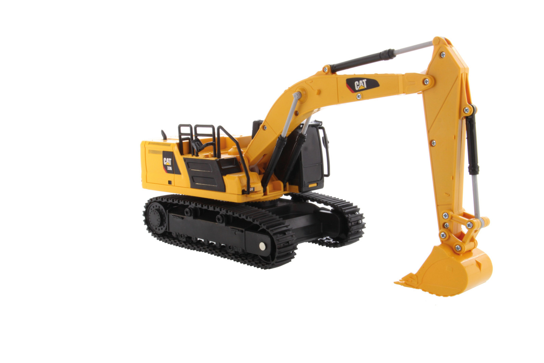 Un juguete excavadora CAT amarillo sobre una superficie blanca, mostrando detalles de la máquina.
