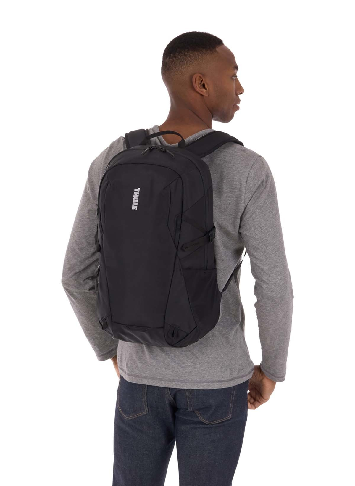 Hombre con una mochila negra. La mochila tiene un logotipo blanco.