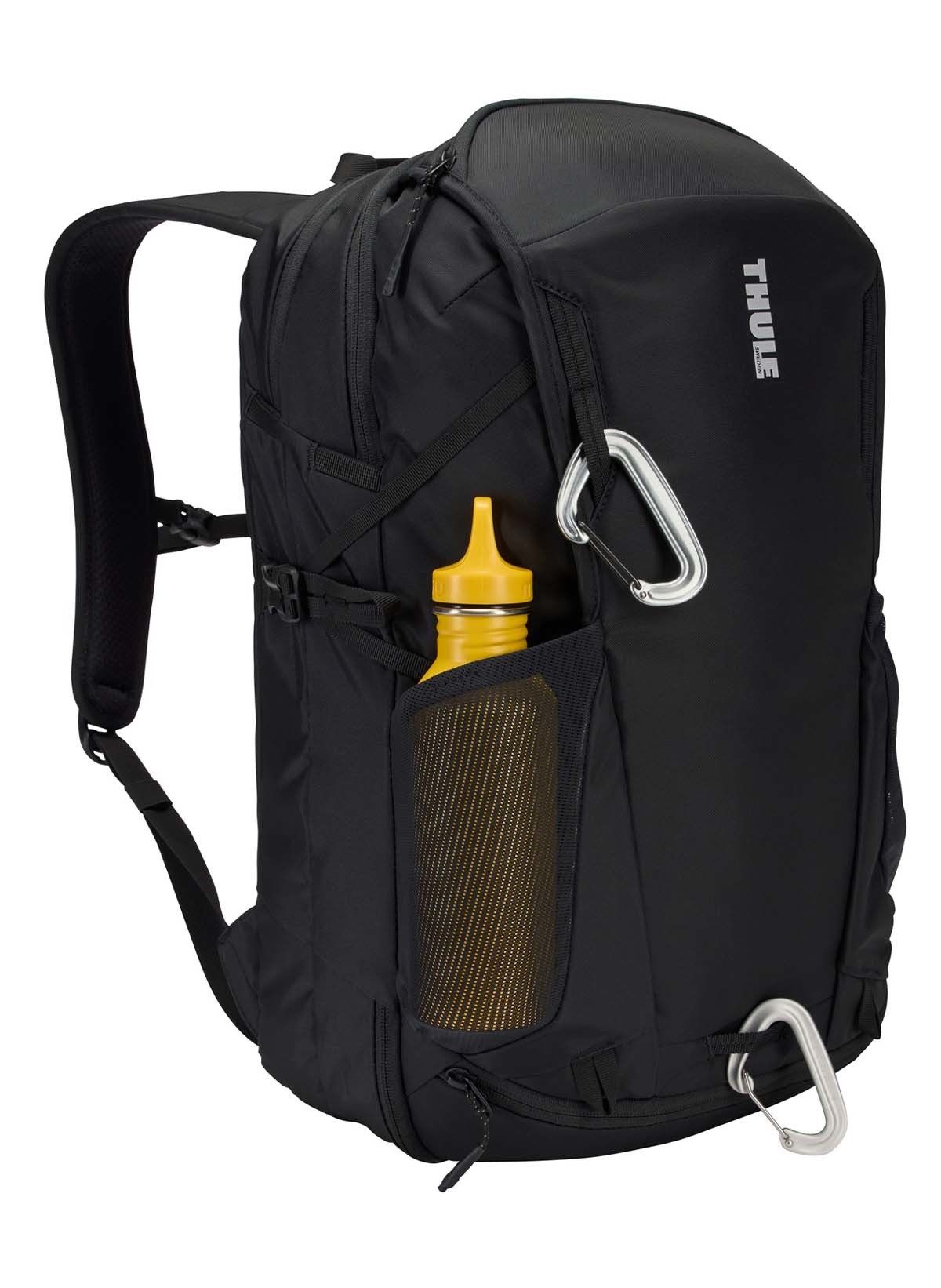 Ein schwarzer Rucksack mit einer gelben Wasserflasche in der Seitentasche und einem Karabiner.