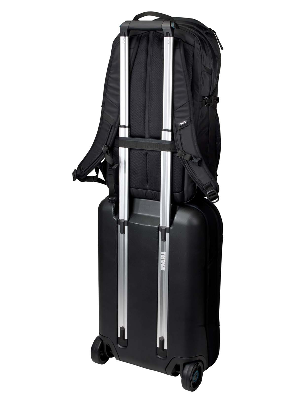Ein schwarzer Rollkoffer mit einem schwarzen Rucksack oben drauf. Der Rucksack hat silberne Griffe.