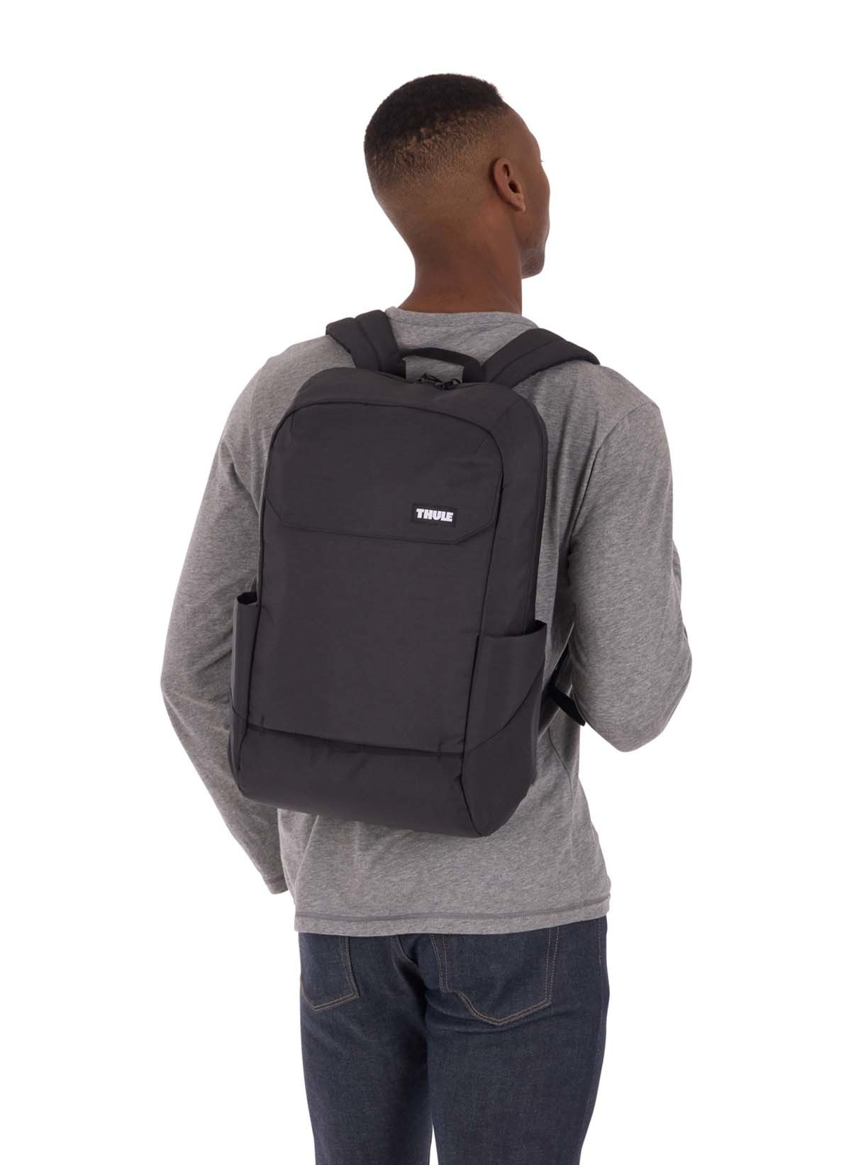 Ein Mann mit einem schwarzen Rucksack. Die Marke ist THULE.