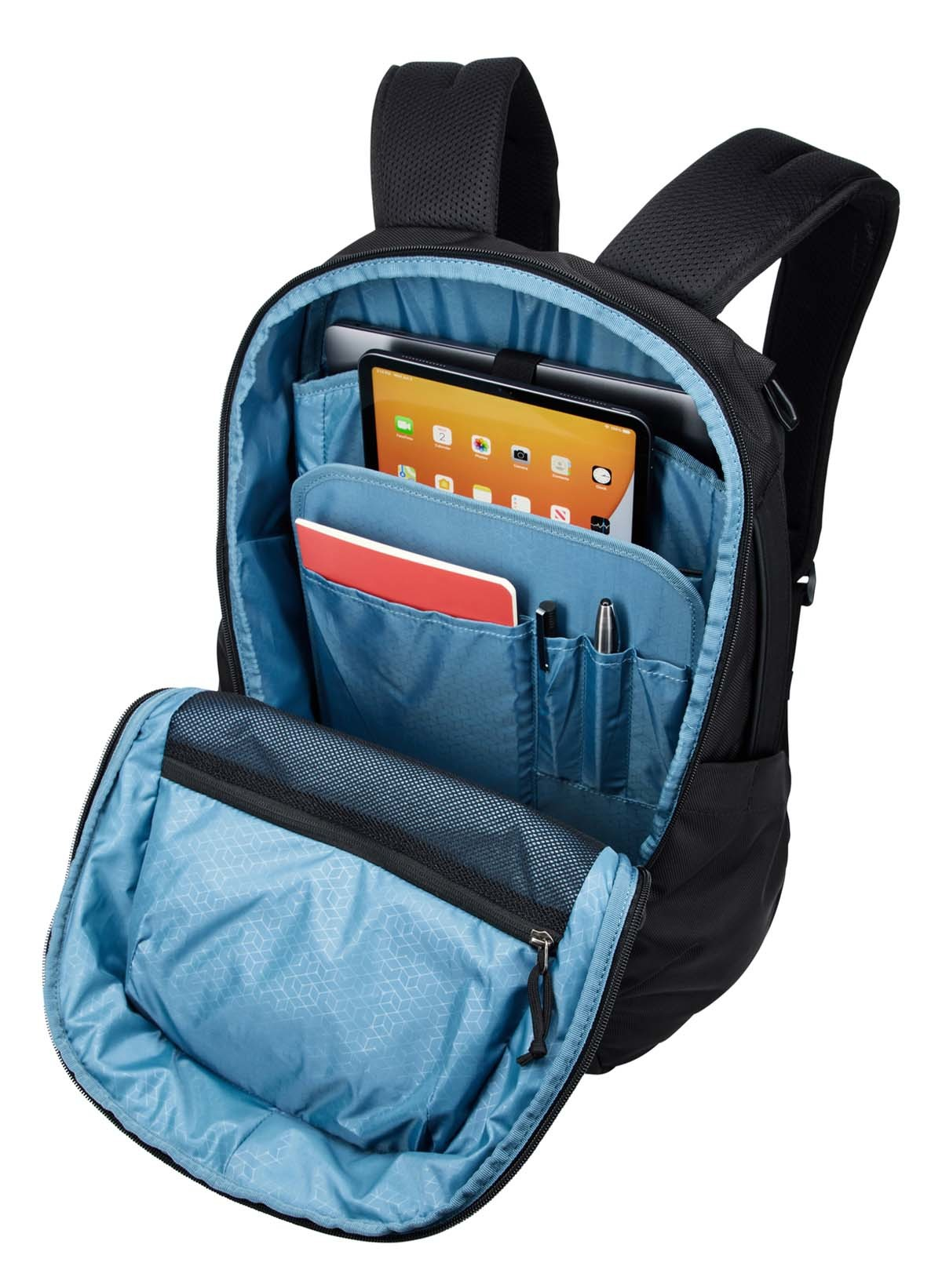 Ein schwarzer Rucksack, geöffnet, um ein Tablet, Notizbuch, Stift und andere Gegenstände in blauem Innenraum zu zeigen.
