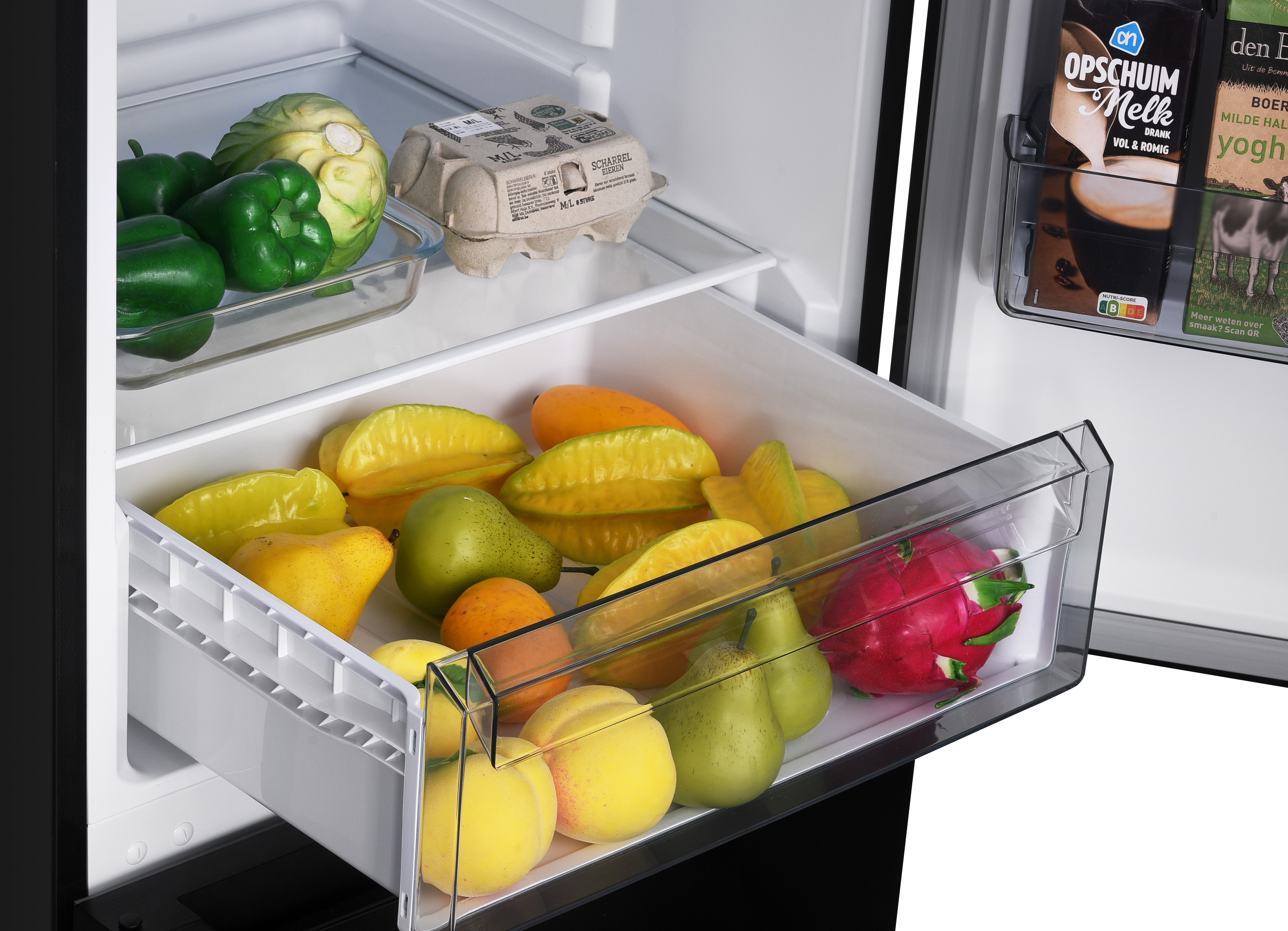 Refrigerator drawer filled with fruits: starfruit, pears, peaches, and dragon fruit.