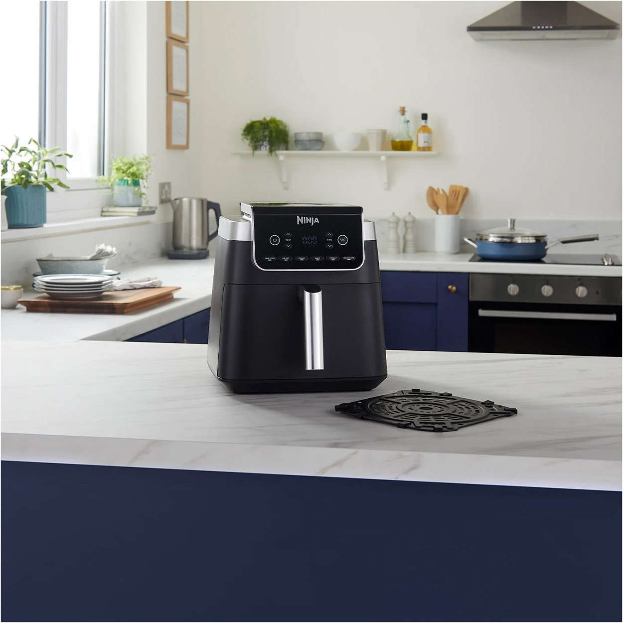 Friggitrice ad aria nera su bancone bianco in cucina. Griglia sul bancone.