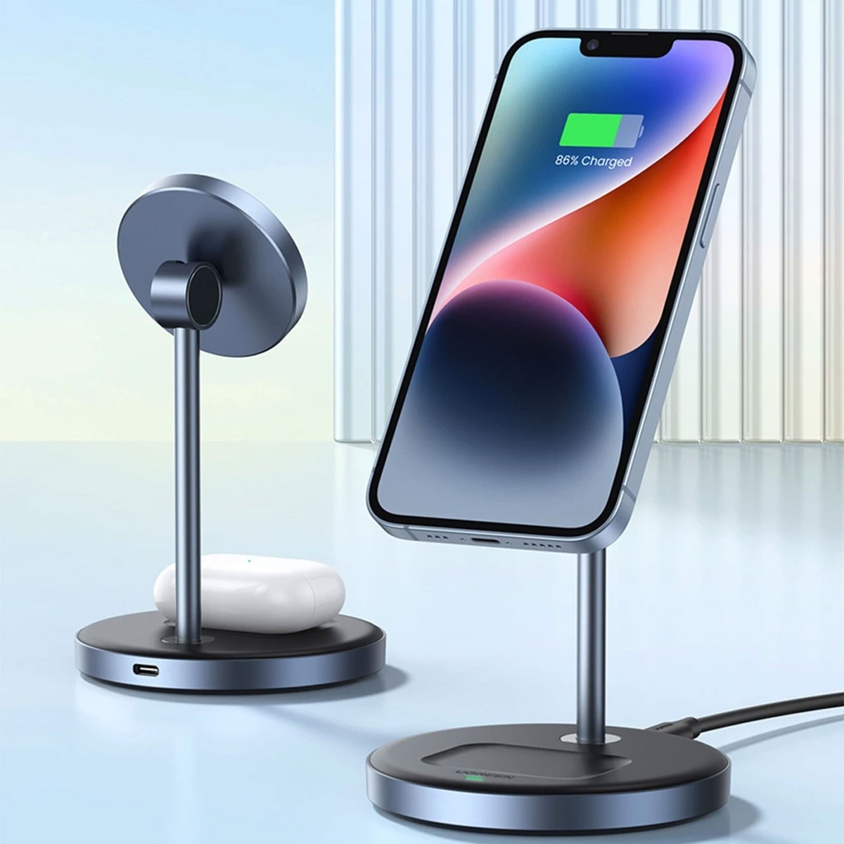 Bir telefon ve AirPods ile şarj standları. Telefon %86 şarj olduğunu gösteriyor. Gri ve siyah tasarım.
