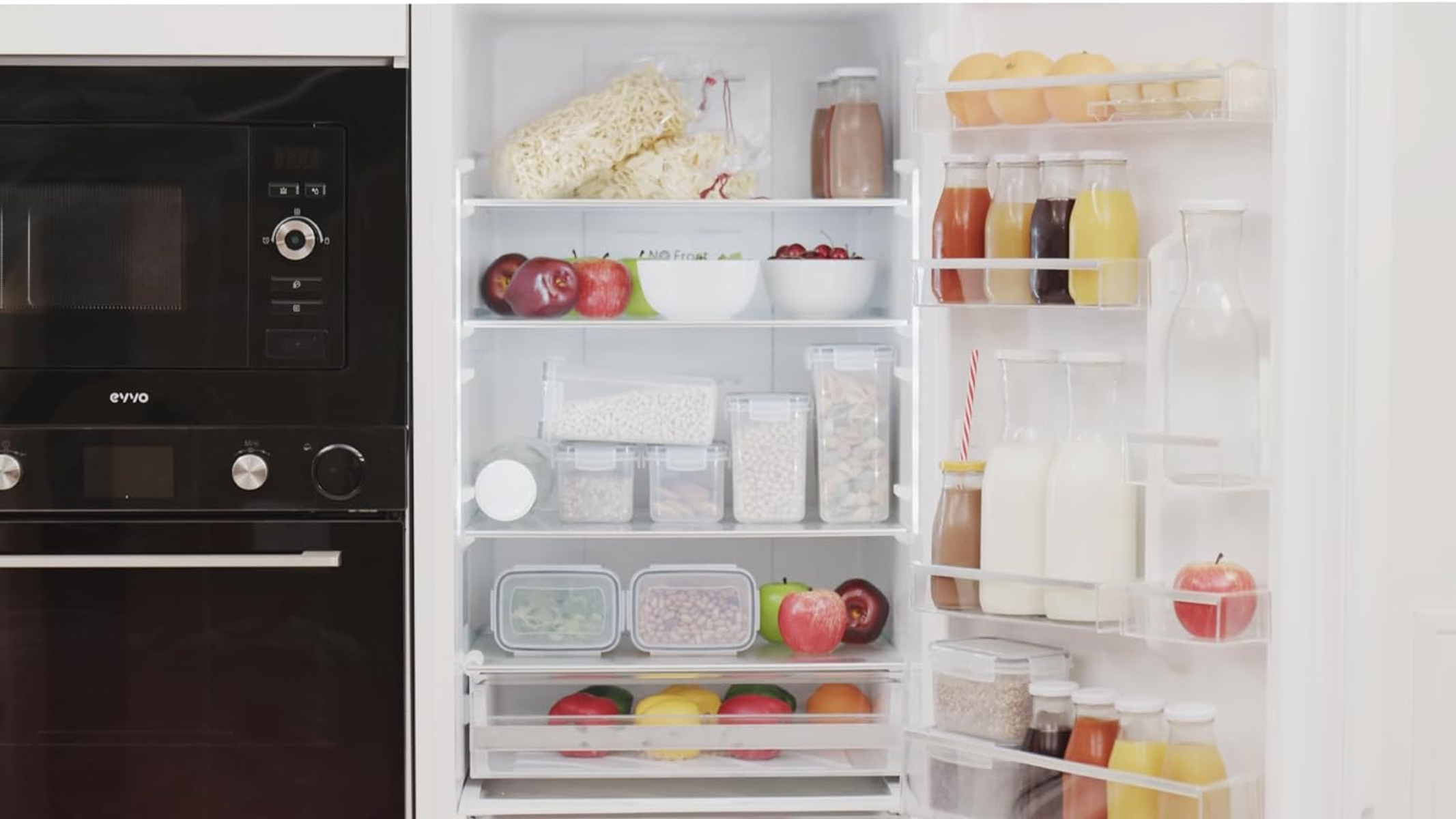 Refrigerador abierto con alimentos. Incluye manzanas, zumo y otros artículos.
