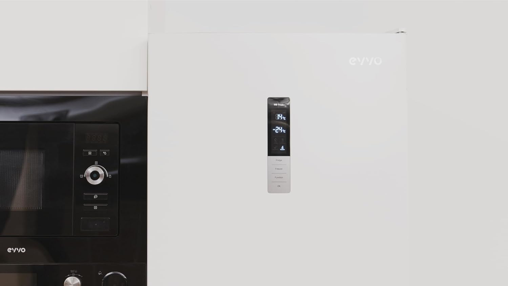 Refrigerador blanco con pantalla digital y microondas negro a la izquierda.