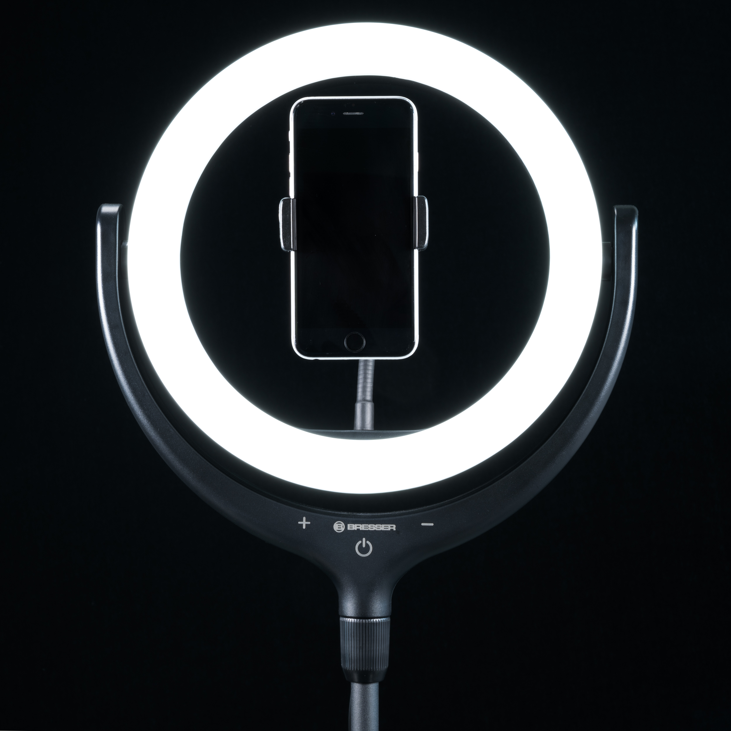 Anillo de luz con soporte para teléfono, sobre un soporte. Fondo negro.