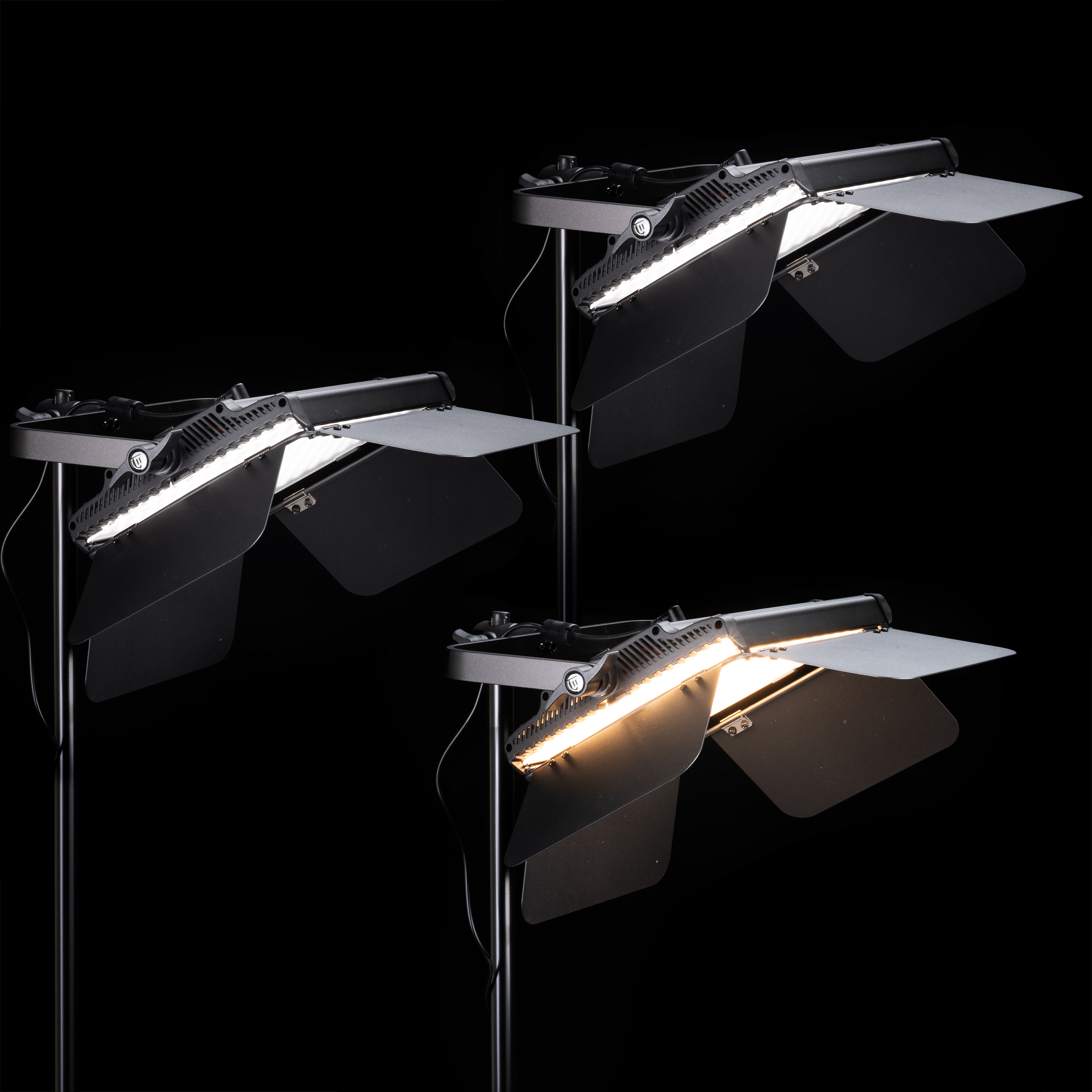 Tres luces de estudio. Cada luz tiene una pantalla negra y un soporte plateado. El fondo es negro.