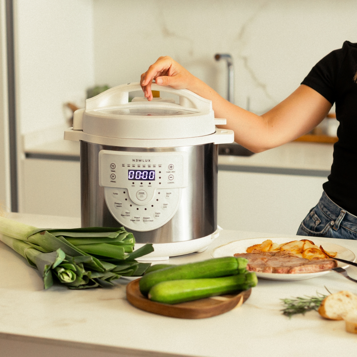 Una persona cerca de una olla a presión en una encimera. Comida y verduras están cerca.