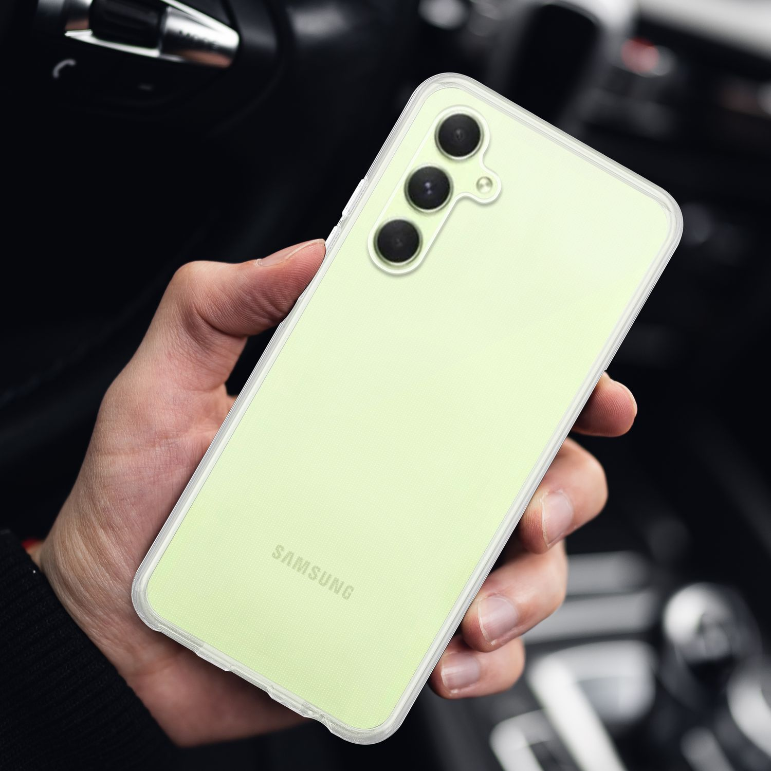 Una mano che tiene un telefono verde chiaro con tre fotocamere posteriori. Logo Samsung.