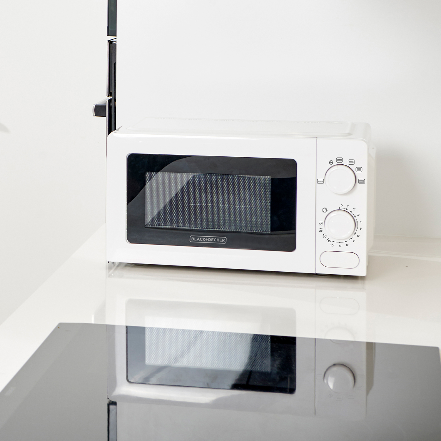 Un horno microondas blanco sobre una superficie reflectante, con detalles y controles negros.