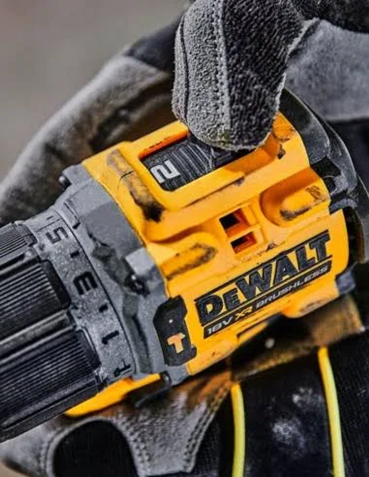 Nahaufnahme einer Hand in einem Handschuh, die einen gelb-schwarzen DeWalt-Bohrer hält. Der Bohrer ist abgewinkelt.
