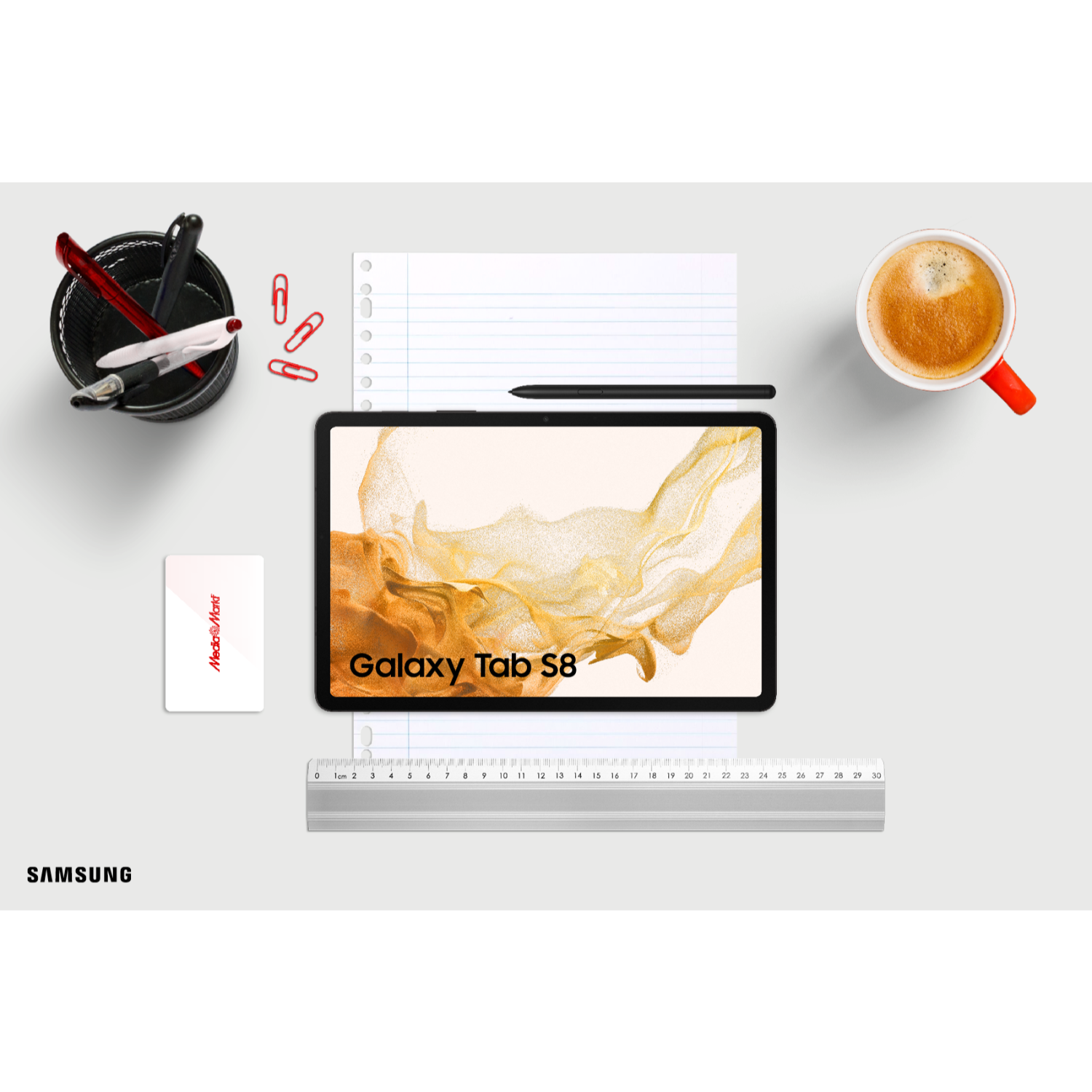 Ein Schreibtisch mit Tablet, Kaffee, Stiften und Büromaterial. Das Tablet zeigt Galaxy Tab S8.