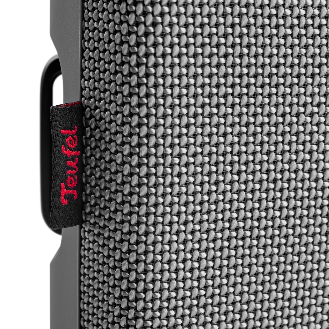 Close-up of a textured speaker fabric with a red 'Teufel' tag, against a gray background.