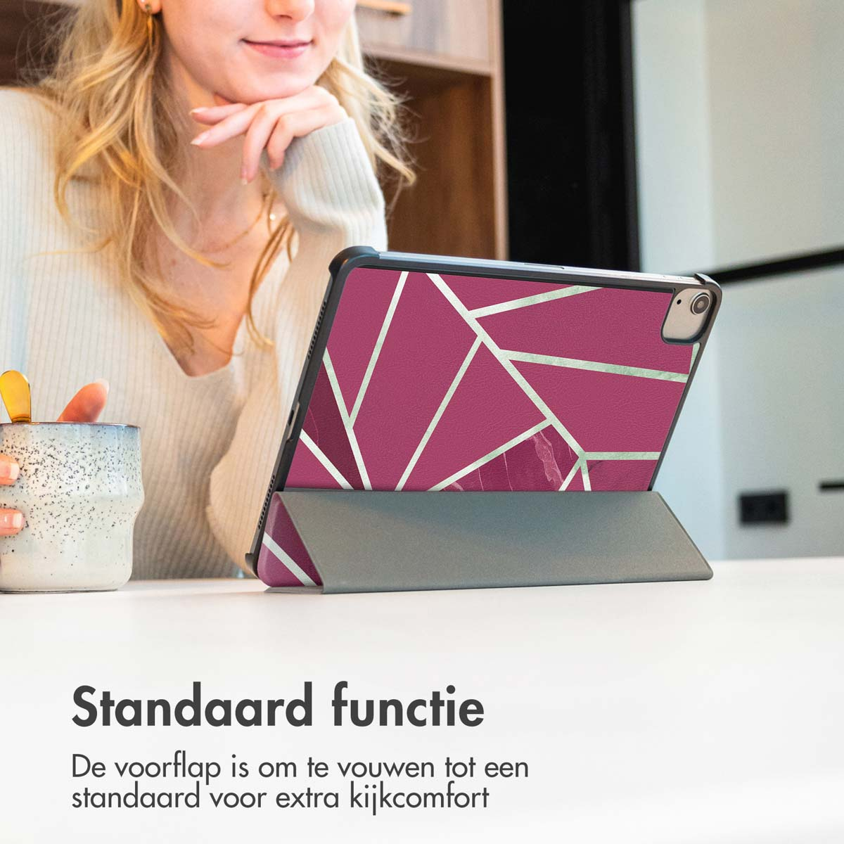 Vrouw met iPad-hoes. Hoes is roze met geometrisch design. Tekst vermeldt de standaard functie.