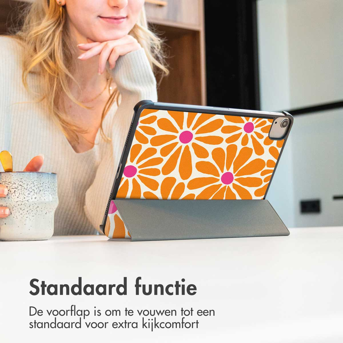 Une femme avec un étui iPad montrant des fleurs oranges, assise sur une table.