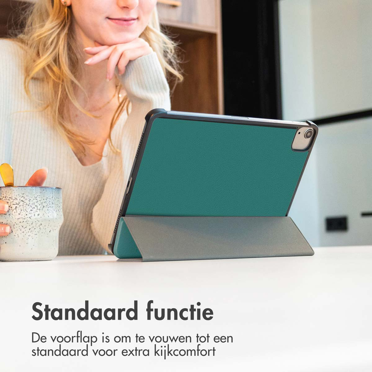 Persoon met een tablet in een standaard. Tablet in een teal hoesje. Tekst: Standaard functie.