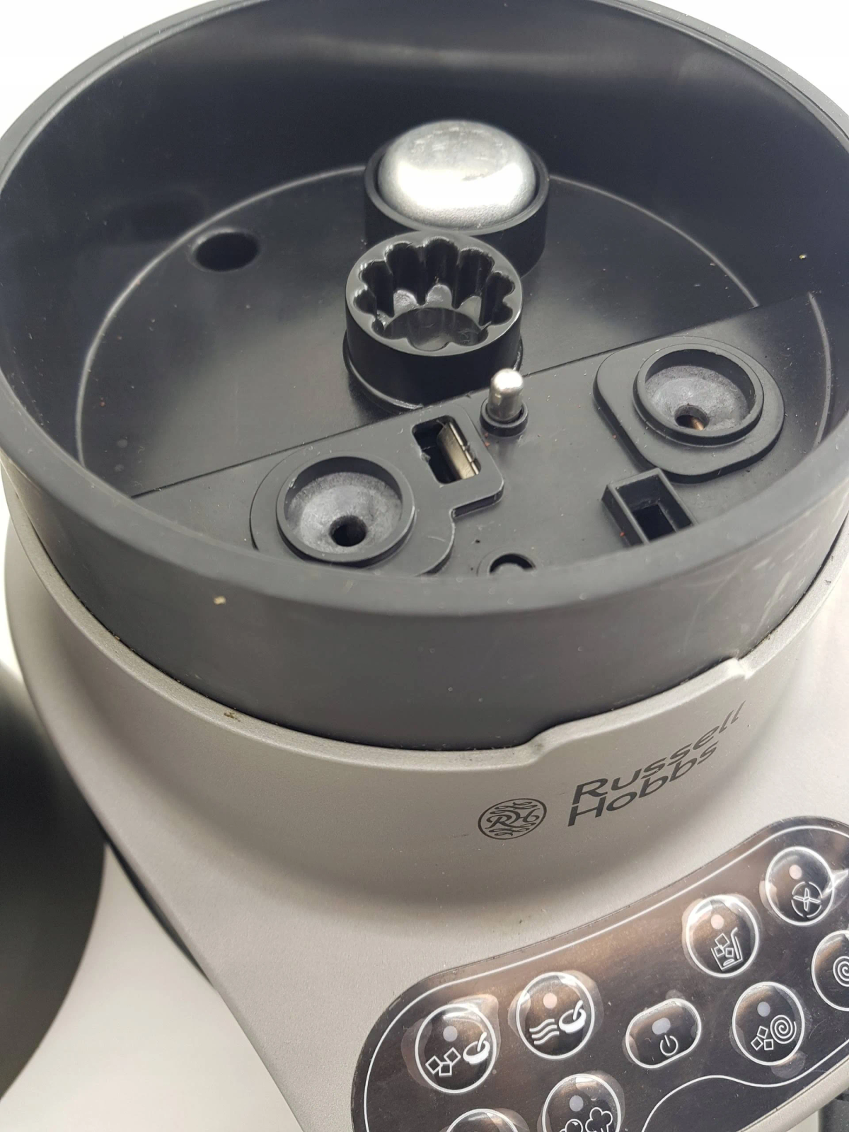 Gros plan de l'intérieur d'un robot culinaire Russell Hobbs. Le couvercle est ouvert, montrant la lame et les mécanismes centraux.