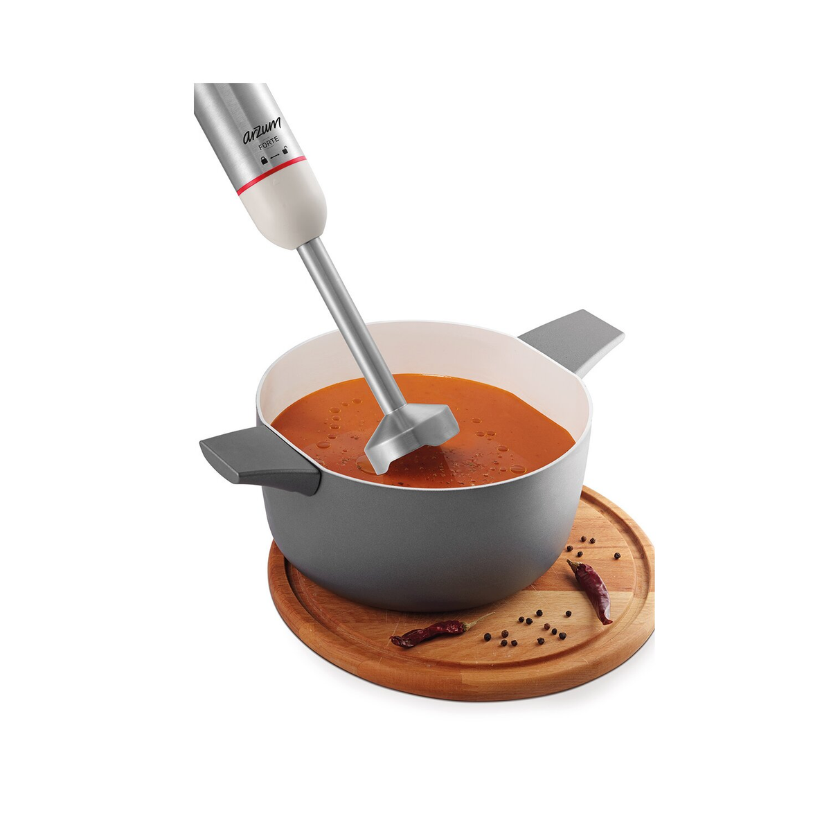 Handmixer in einem grauen Topf mit Suppe. Holzbrett mit Gewürzen daneben.