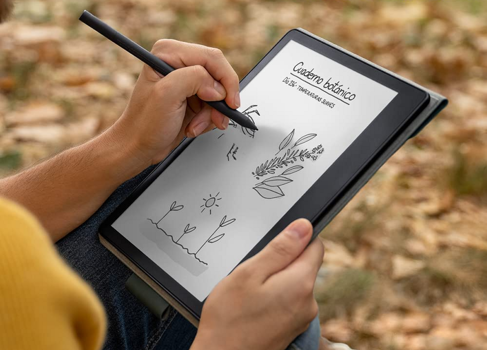 Una persona escribe en una tableta con un lápiz óptico. La tableta dice 'Cuaderno botanico'.
