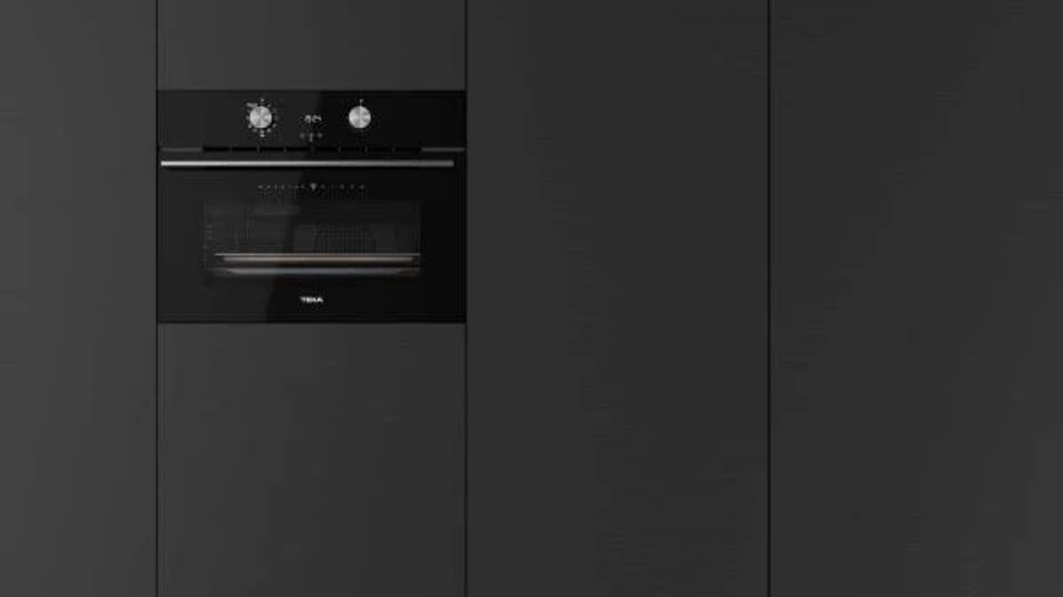 Horno negro empotrado en un armario de cocina gris oscuro. El horno tiene controles y puerta de cristal.