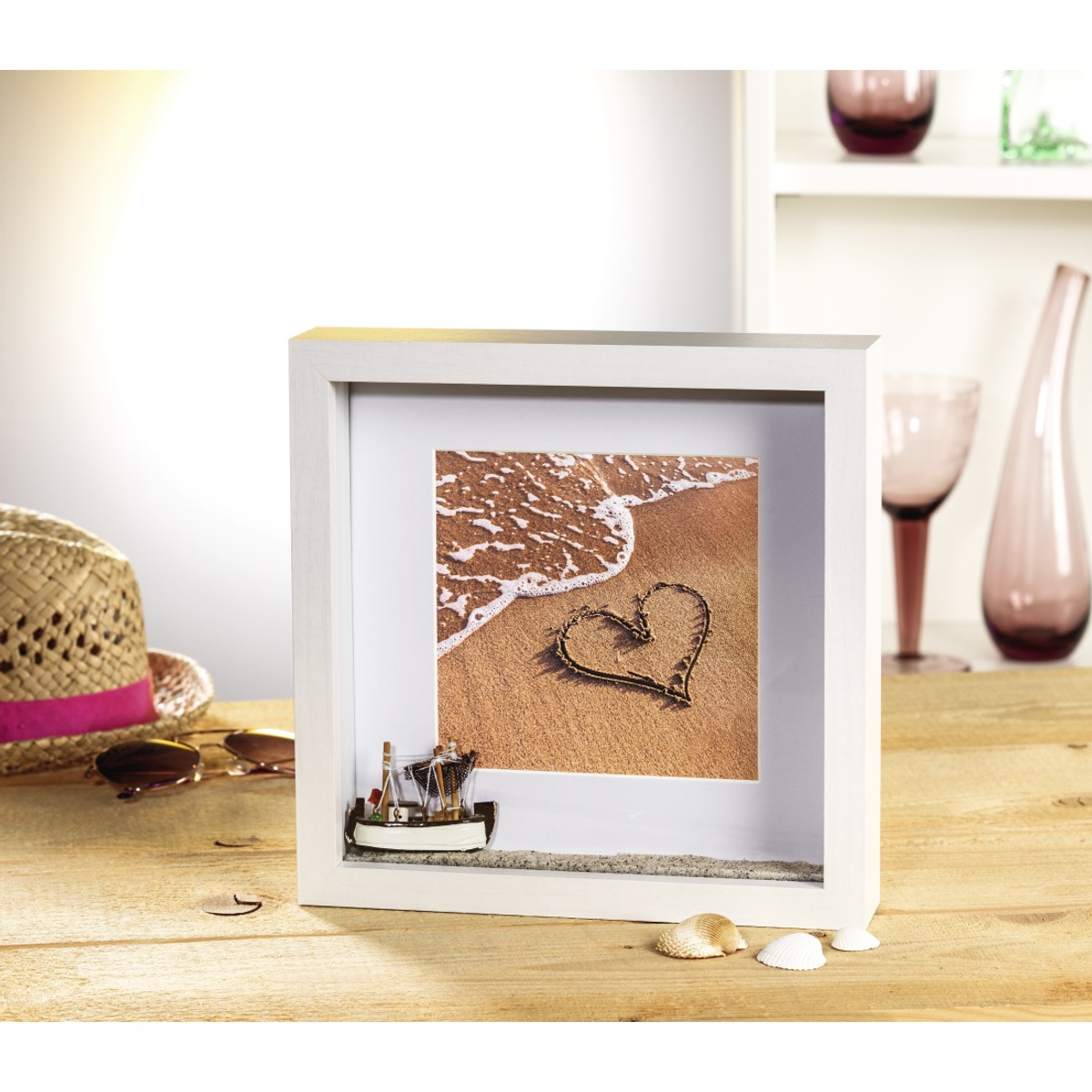 Gerahmtes Bild mit Herz im Sand am Strand und kleinem Boot.