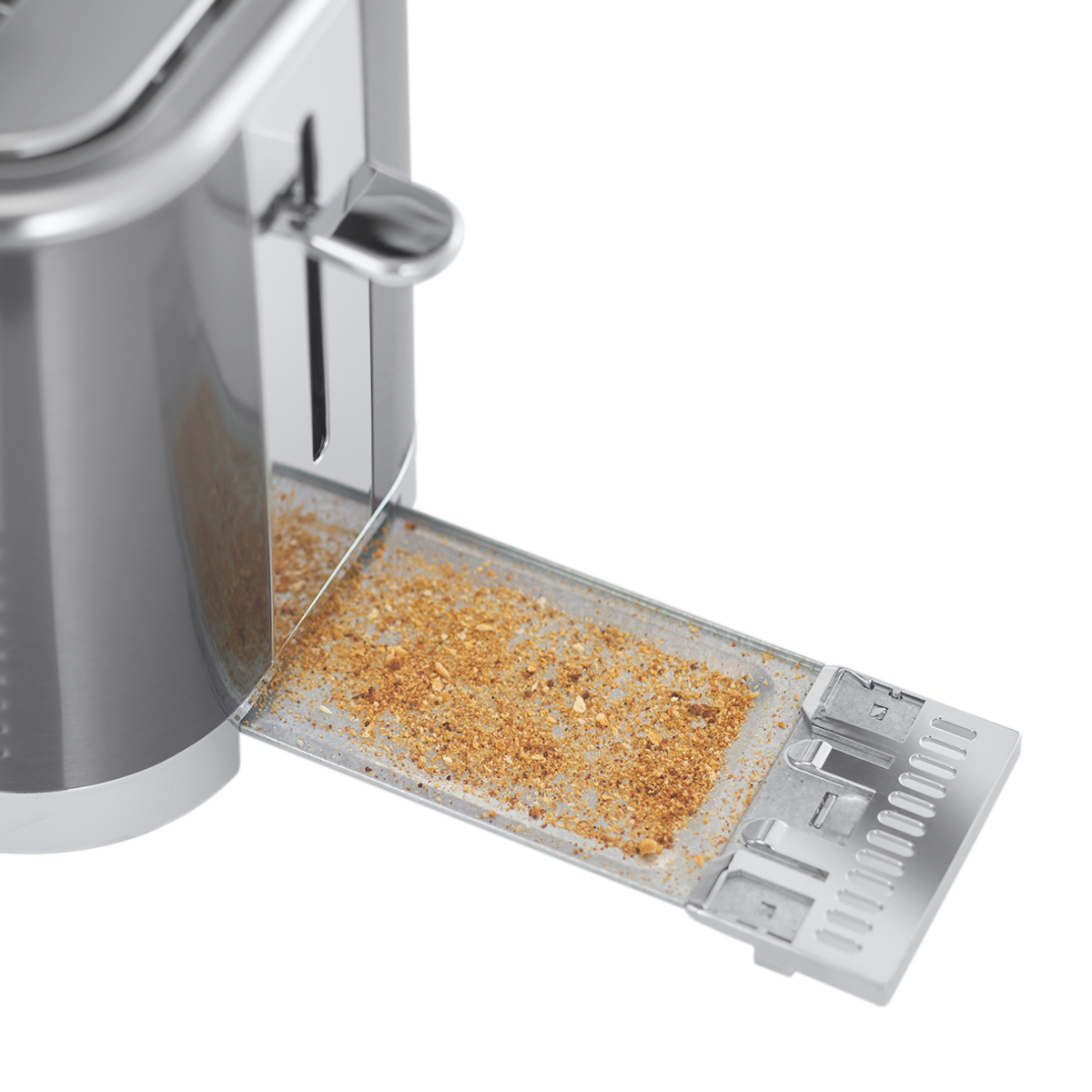 Chromowany toster z otwartą szufladą na okruchy. Widoczne okruchy. Tło jest białe.
